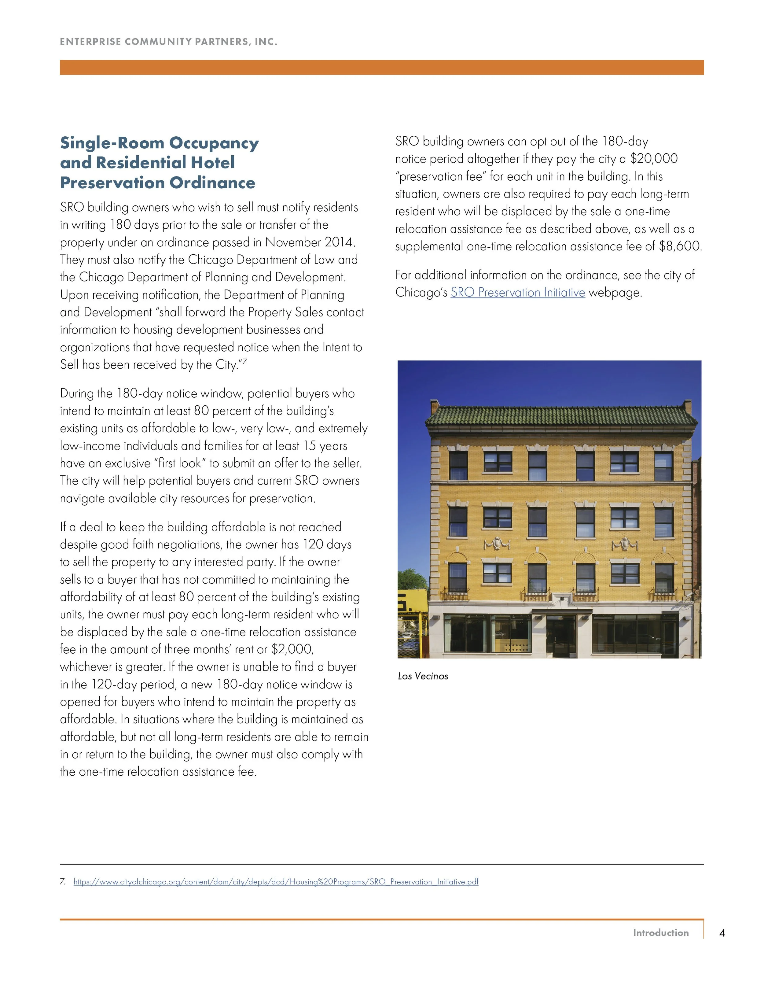 Colorful, multi-story residential building with large windows, green roof, and storefront at street level, located in Los Vecinos neighborhood.