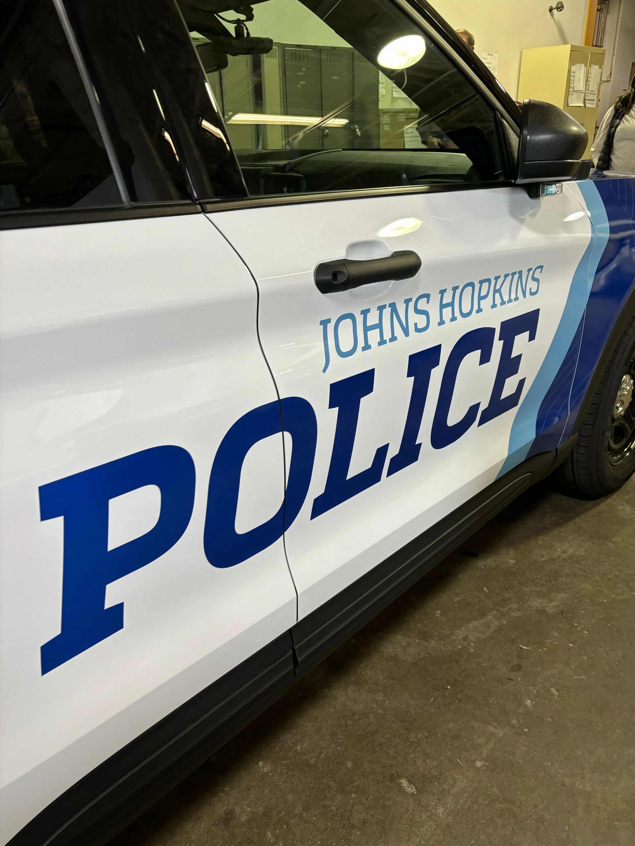 A Johns Hopkins Police vehicle inside a building or garage, showing the side door with the police insignia and text.