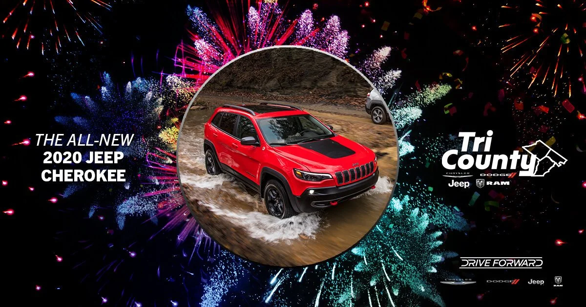 Fireworks display in the background with a red 2020 Jeep Cherokee in the center, driving through water. The image promotes the Jeep Cherokee at Tri-County.
