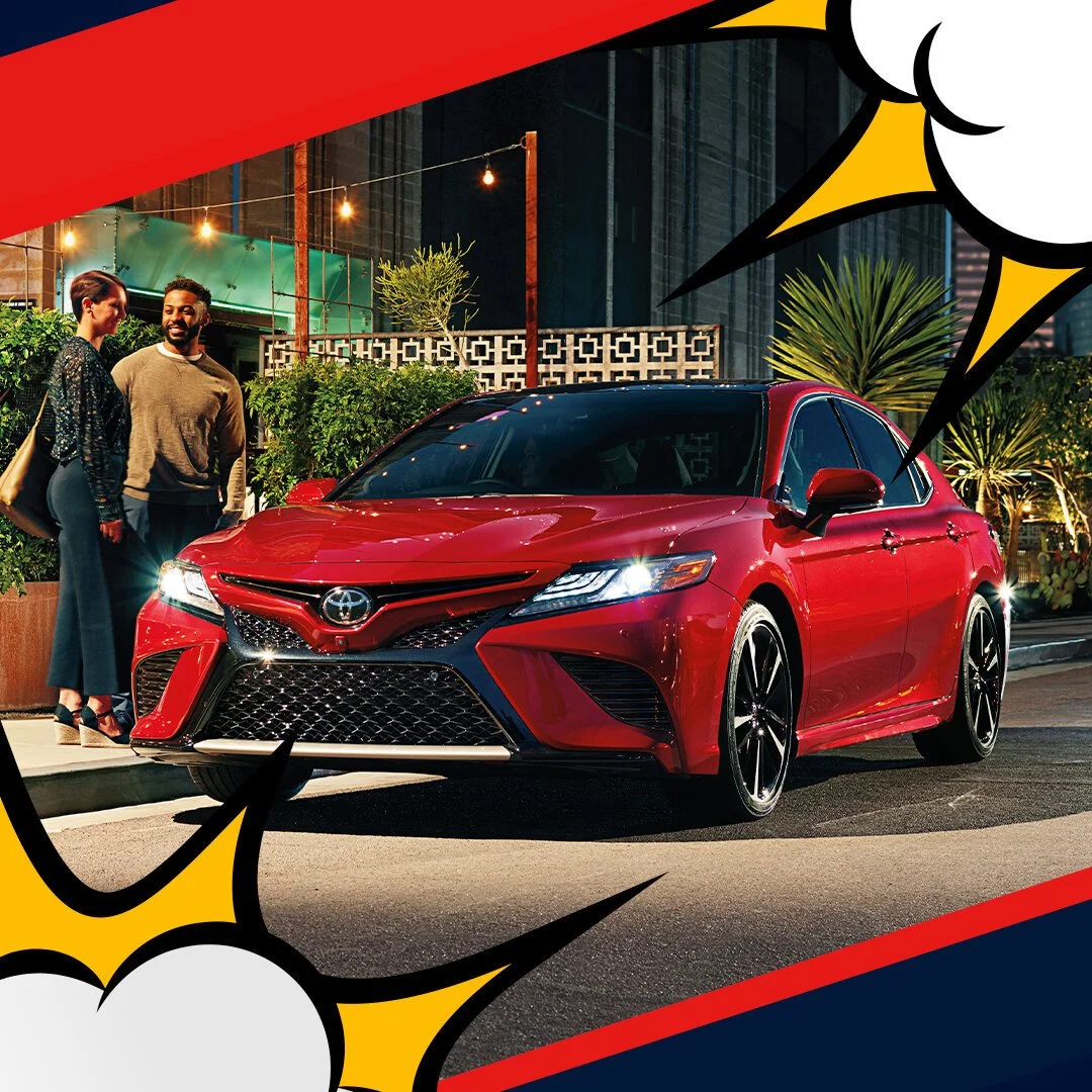 A red Toyota Camry parked on a city street at night, with two people dressed in business casual standing nearby, engaging in conversation, surrounded by plants and streetlights, with comic-style speech bubbles and borders.