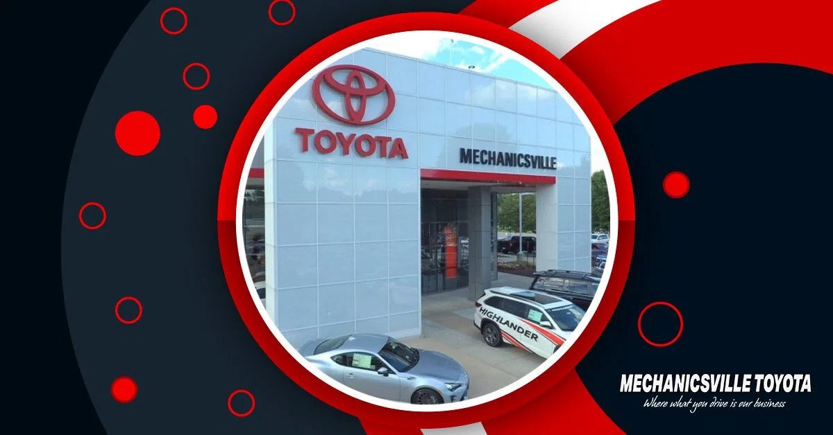 Exterior view of a Toyota dealership building in Mechanicville, displaying the Toyota logo and vehicles including a Highlander SUV and a sports car in front of the dealership.