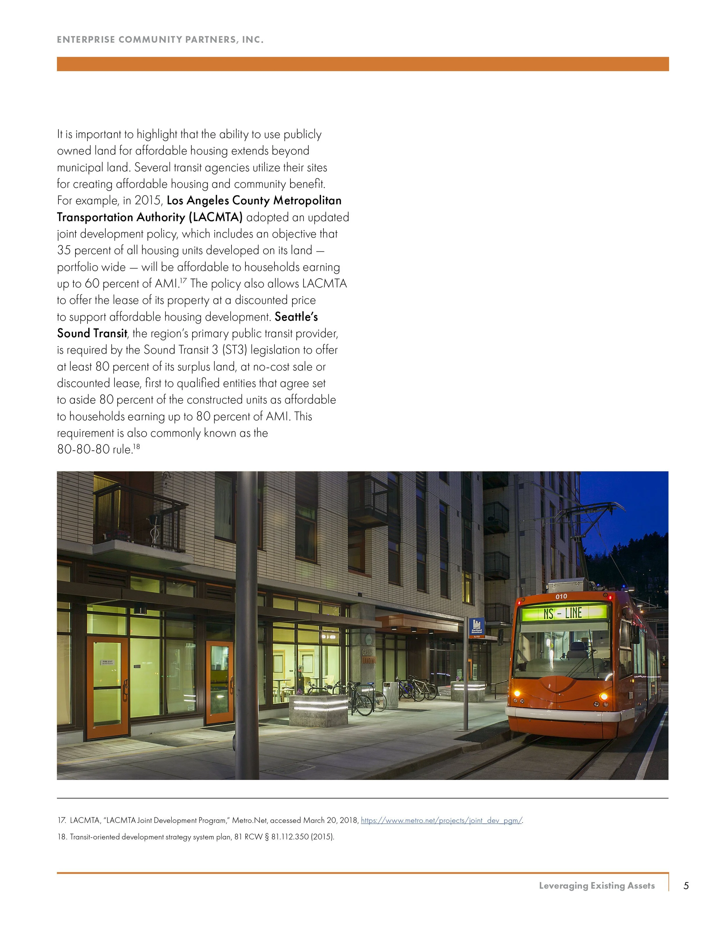 Photo of a modern urban building with a bus stop and a red trolleybus on the street during evening hours.