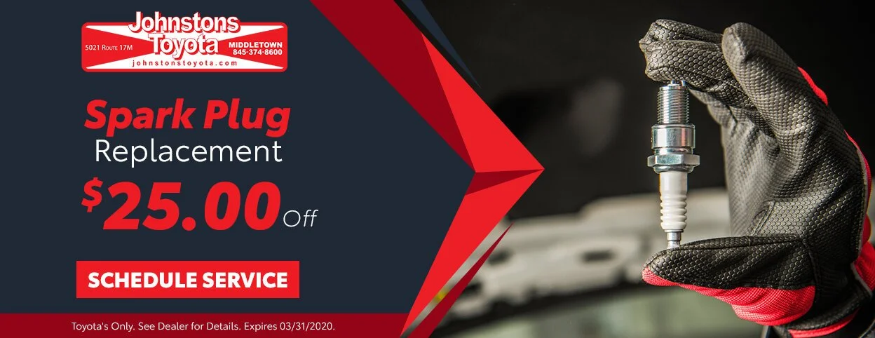 Advertisement for Johnstons Toyota offering $25 off on spark plug replacement, featuring a mechanic's hand holding a spark plug.