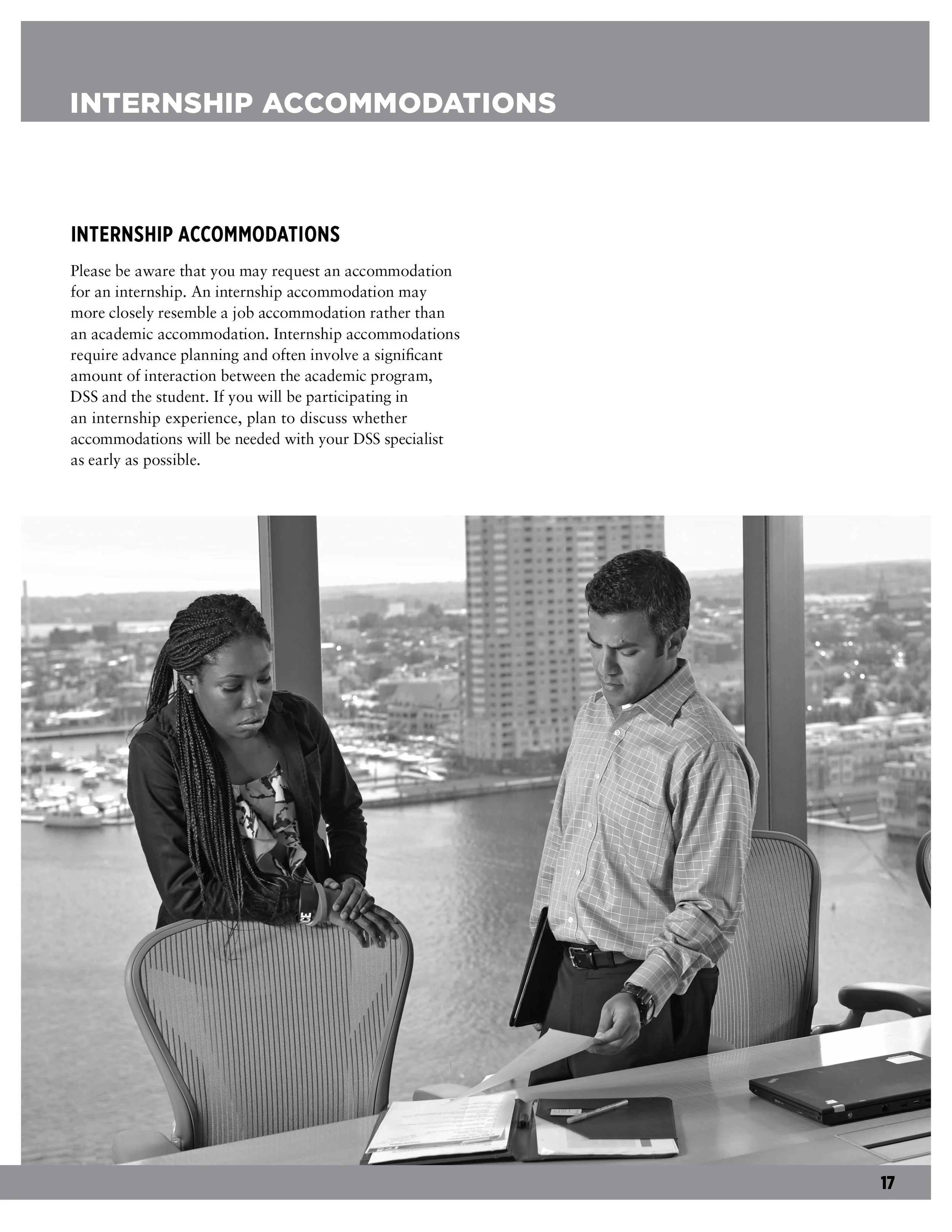 Two people in a professional office setting looking at documents with a city view in the background.