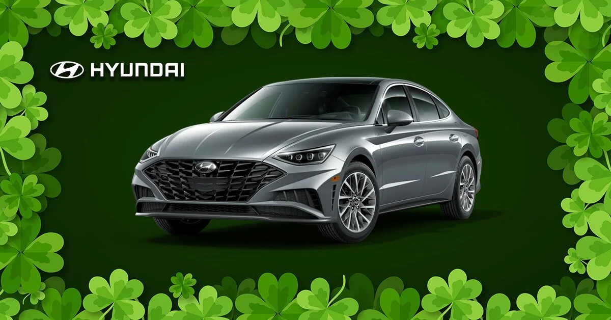 Gray Hyundai sedan in front of a green background with shamrock-shaped leaves and the Hyundai logo.