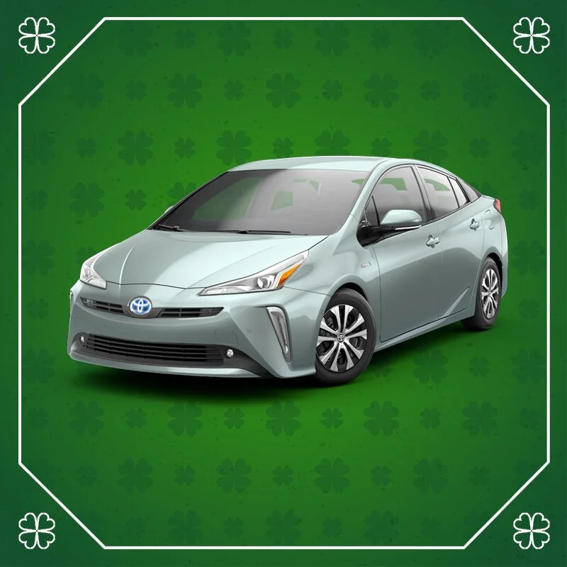 A silver Toyota Prius car against a green background with shamrock patterns.