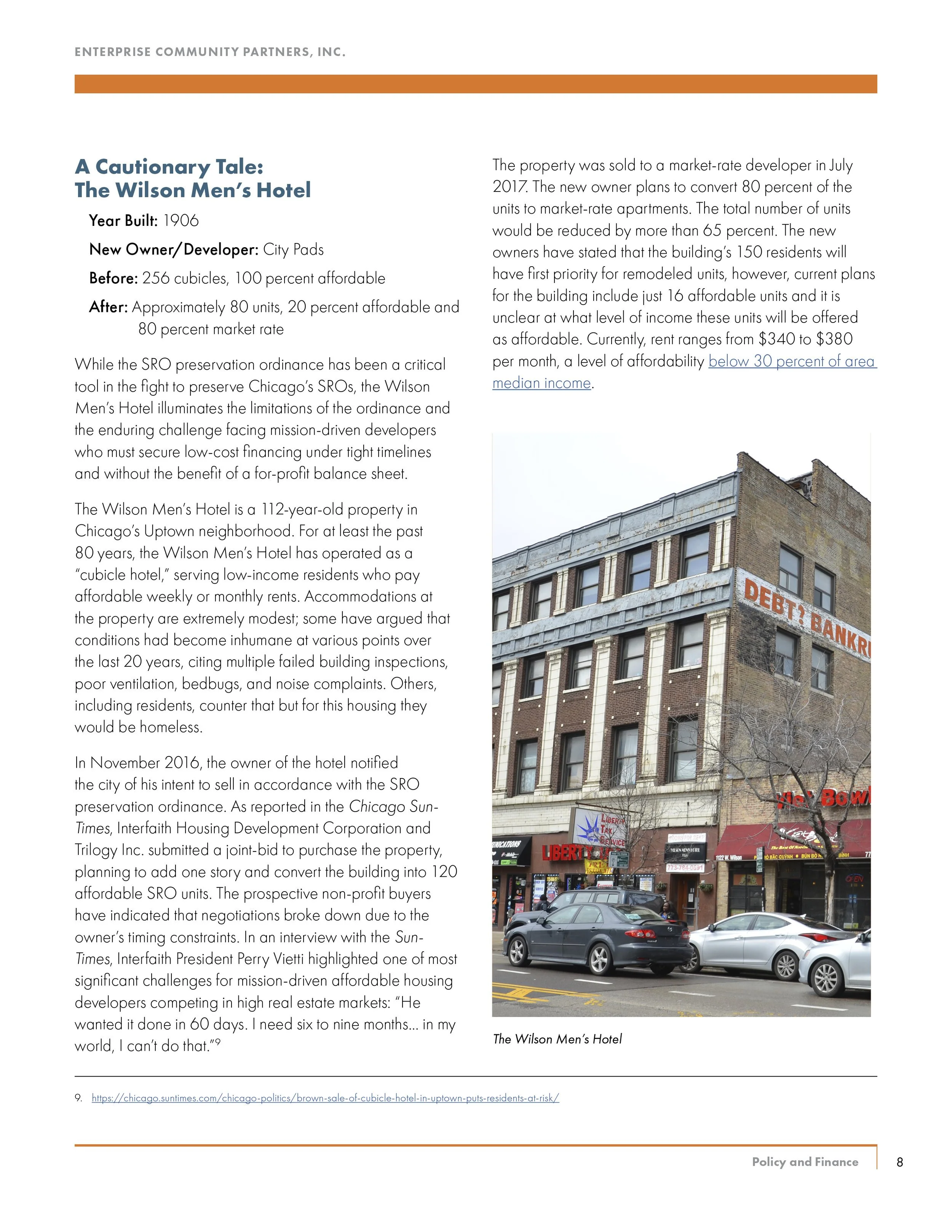 A photo of The Wilson Men's Hotel, a 112-year-old brick building with retail stores on the ground floor and a large 'DEBT BANKR' sign on the side. Several cars are parked in front of the building.