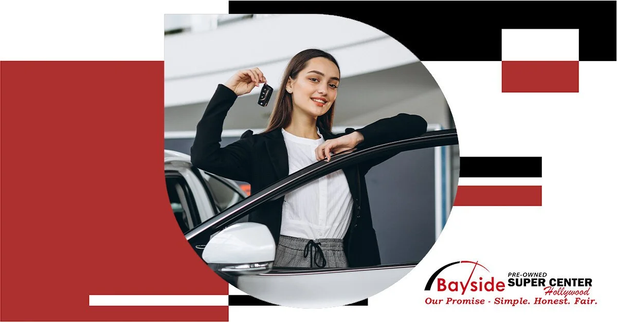 A woman holding car keys and leaning on a white car at a dealership, with promotional graphics and text for Bayside Super Center in Hollywood, offering pre-owned vehicles.