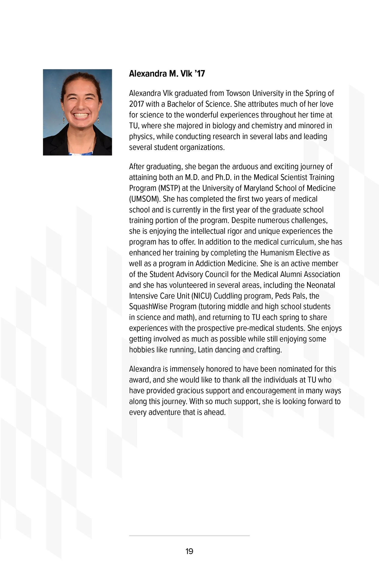 Profile photo of Alexandra M. Vlk, smiling woman with brown hair tied back, wearing a black blazer and earrings.