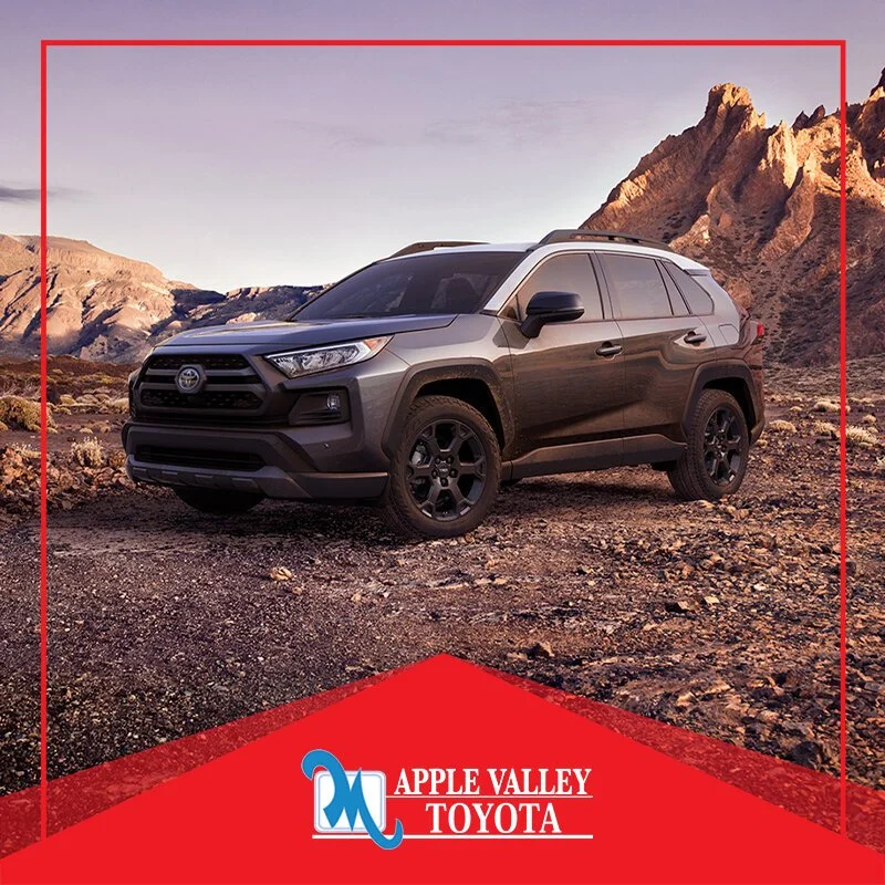 A black Toyota RAV4 parked on a desert landscape with mountains in the background, sunset lighting, and the Apple Valley Toyota logo at the bottom.
