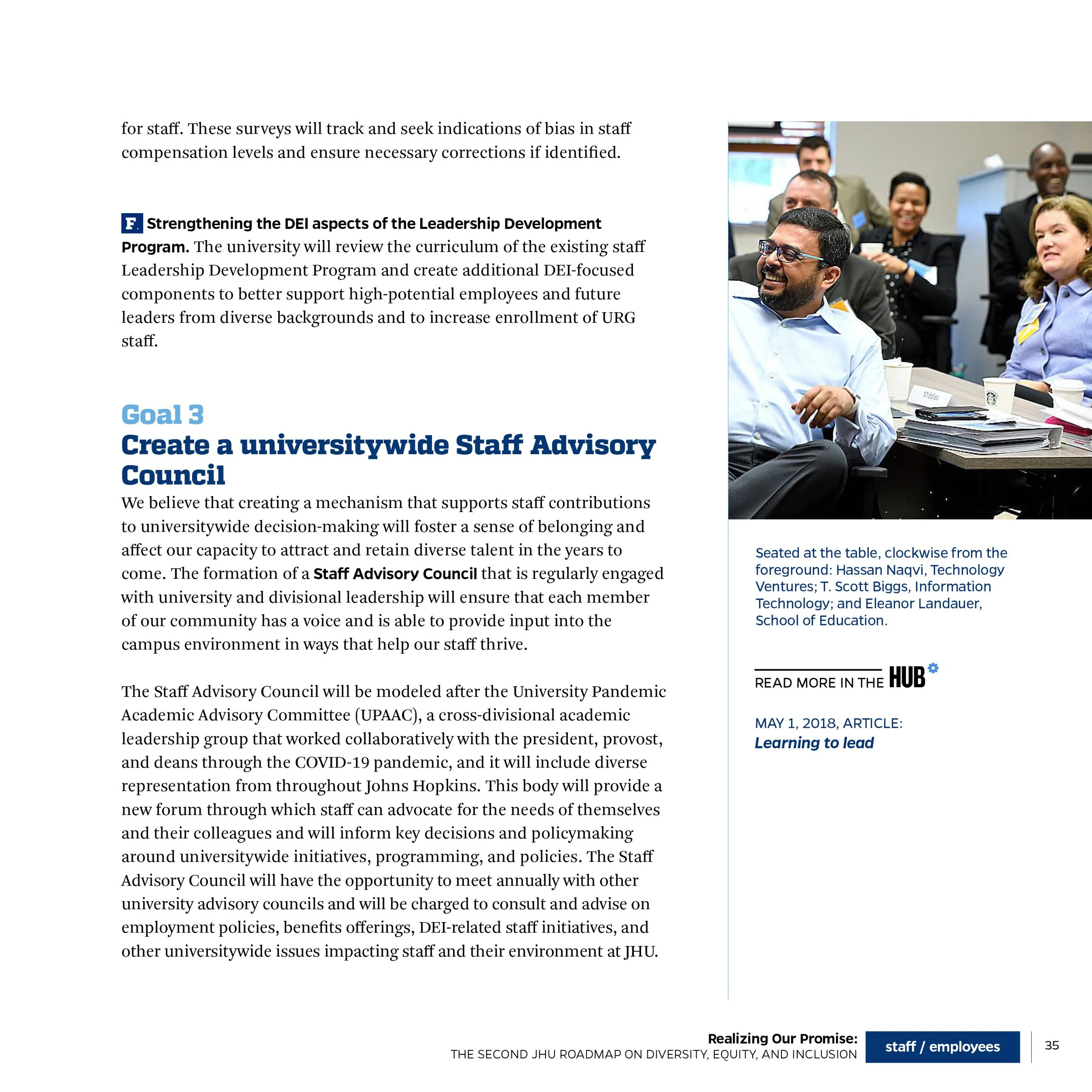 Photograph of a diverse group of people attending a meeting or conference, sitting at a table with documents and coffee cups, with a caption indicating they are seated at the table, clockwise from the foreground: Hassan Naqvi, T. Scott Biggs, and Ele