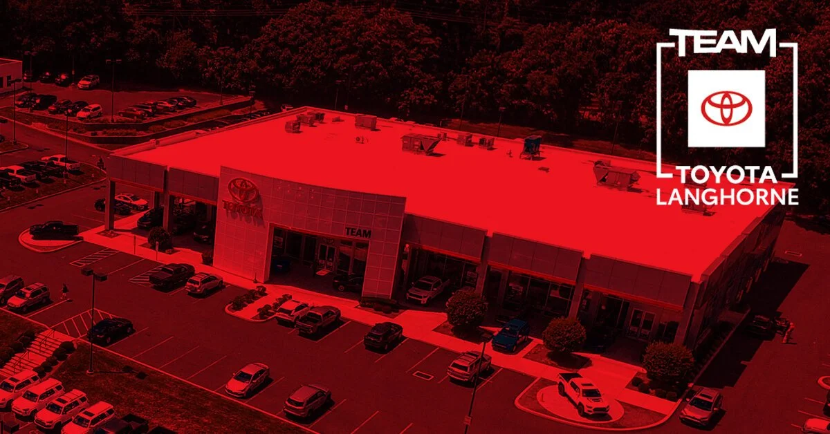 Aerial view of a Toyota dealership building with parking lot. The image has a red overlay and the Toyota logo with text indicating 'Team Toyota Langhorne' at the top right.