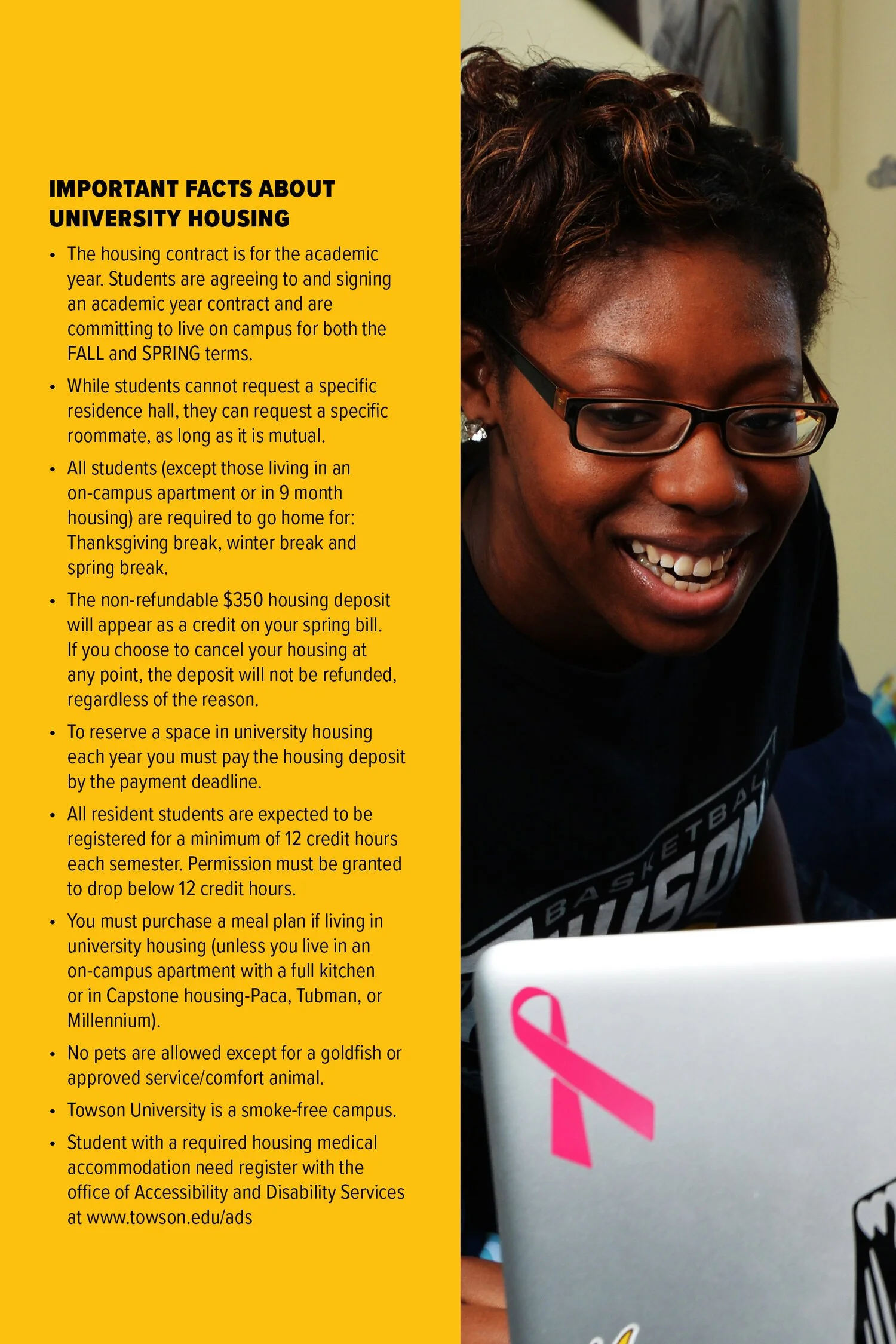 A person with glasses smiling while looking at a laptop with a pink ribbon sticker on it. The laptop is partially visible.