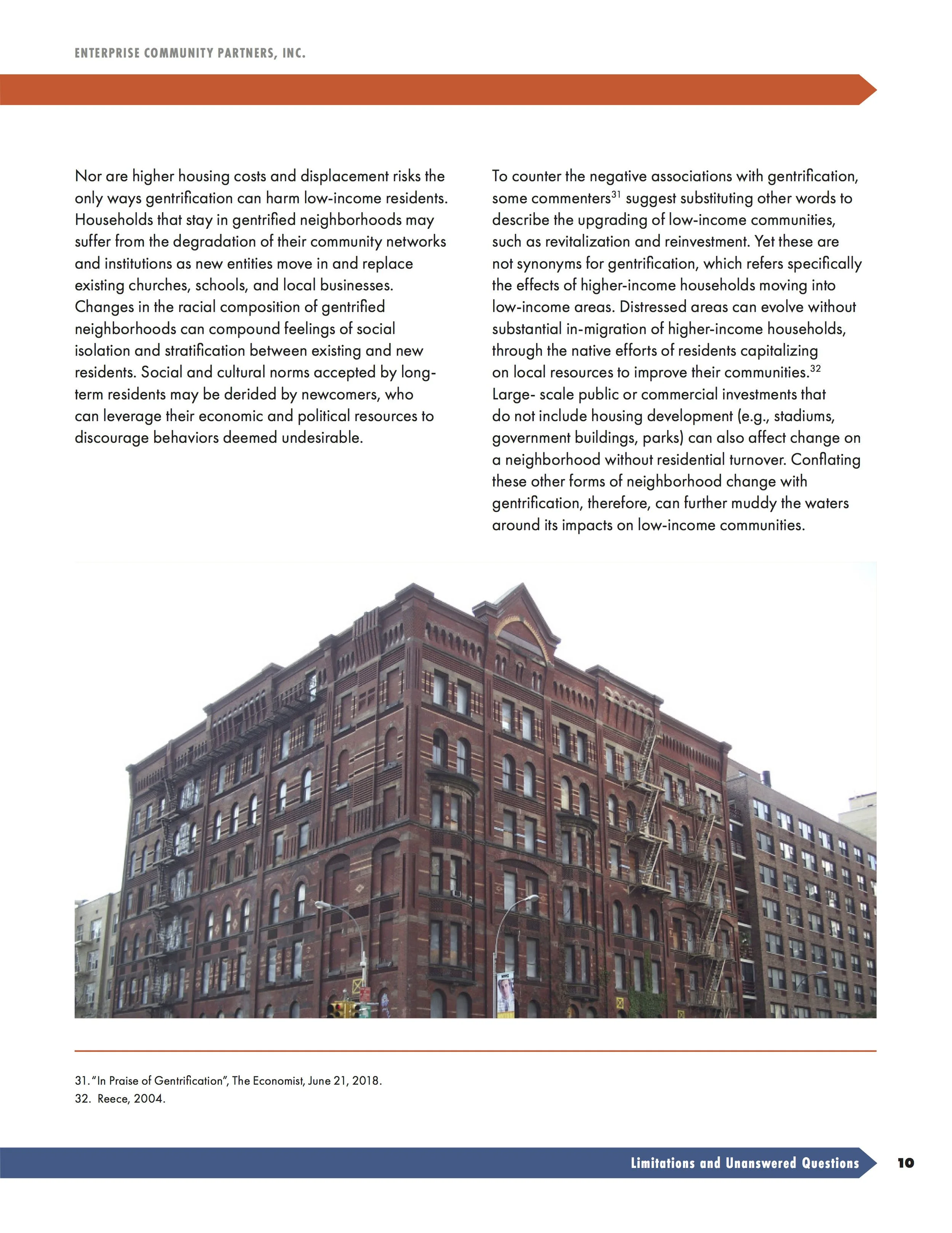 A multiple-story red brick building with fire escapes on the exterior facing the street, parked cars, and street lamps in front.