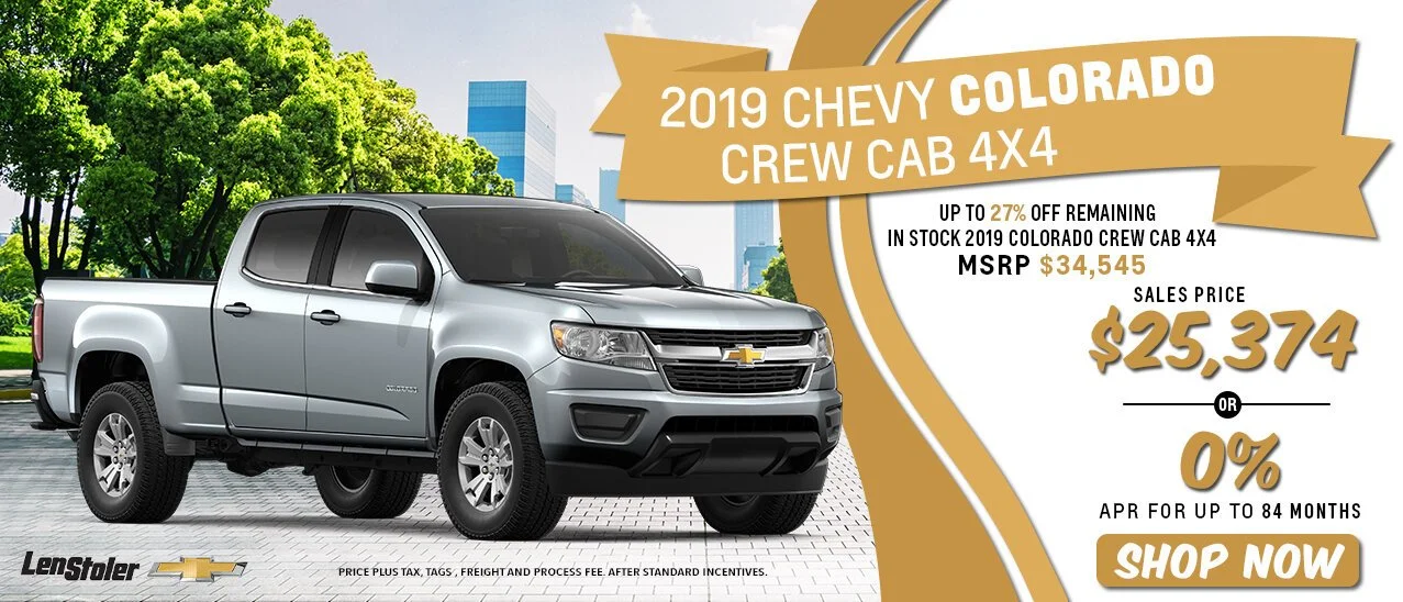 Advertisement for a 2019 Chevrolet Colorado Crew Cab 4x4 in silver, with pricing and promotional details, set against an urban park background with green trees and city buildings.