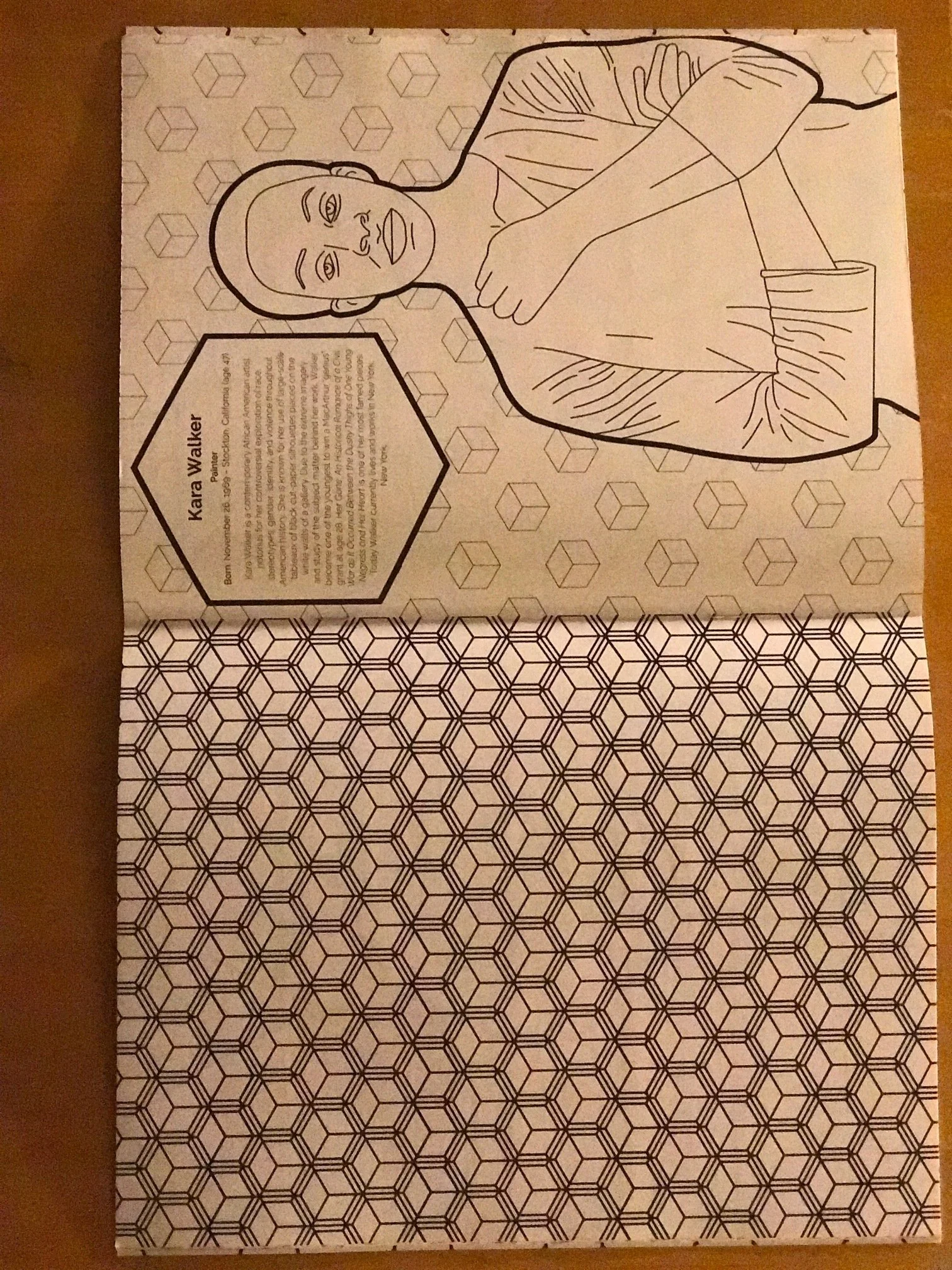 Black and white coloring page of a woman with short hair, wearing a blouse with puffed sleeves, holding her arms crossed. An inset hexagon contains biographical text about an artist named Kara Walker.