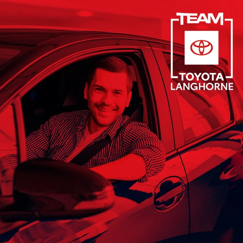 A smiling man sitting in the driver's seat of a red car, with a 'Team Toyota Langhorne' logo in the upper right corner.