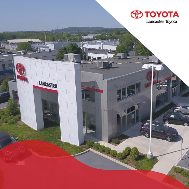 Aerial view of a Toyota car dealership building with the Lancaster Toyota sign, parking lot, and surrounding greenery.