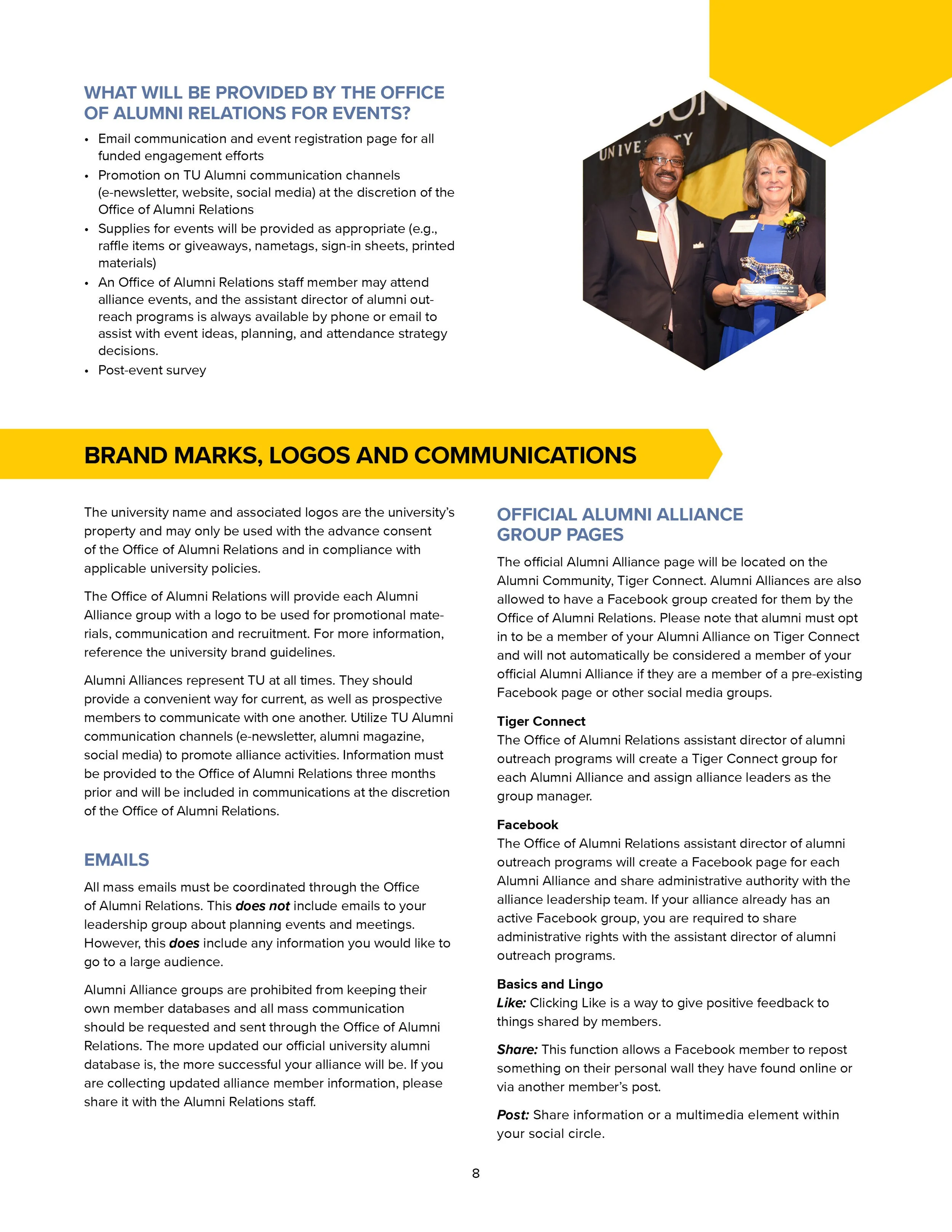 A man in a dark suit and tie standing next to a woman in a dark blazer and blue dress, both smiling, at an award ceremony.