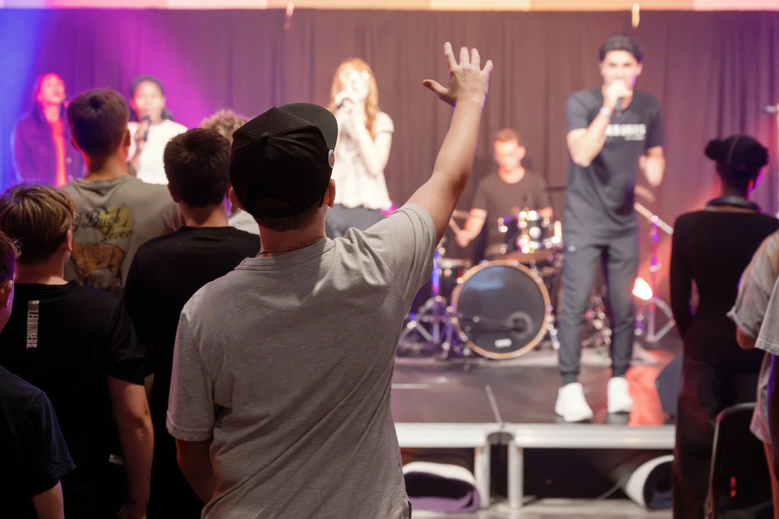 An audience participating in a worship service, while a band plays in the background.