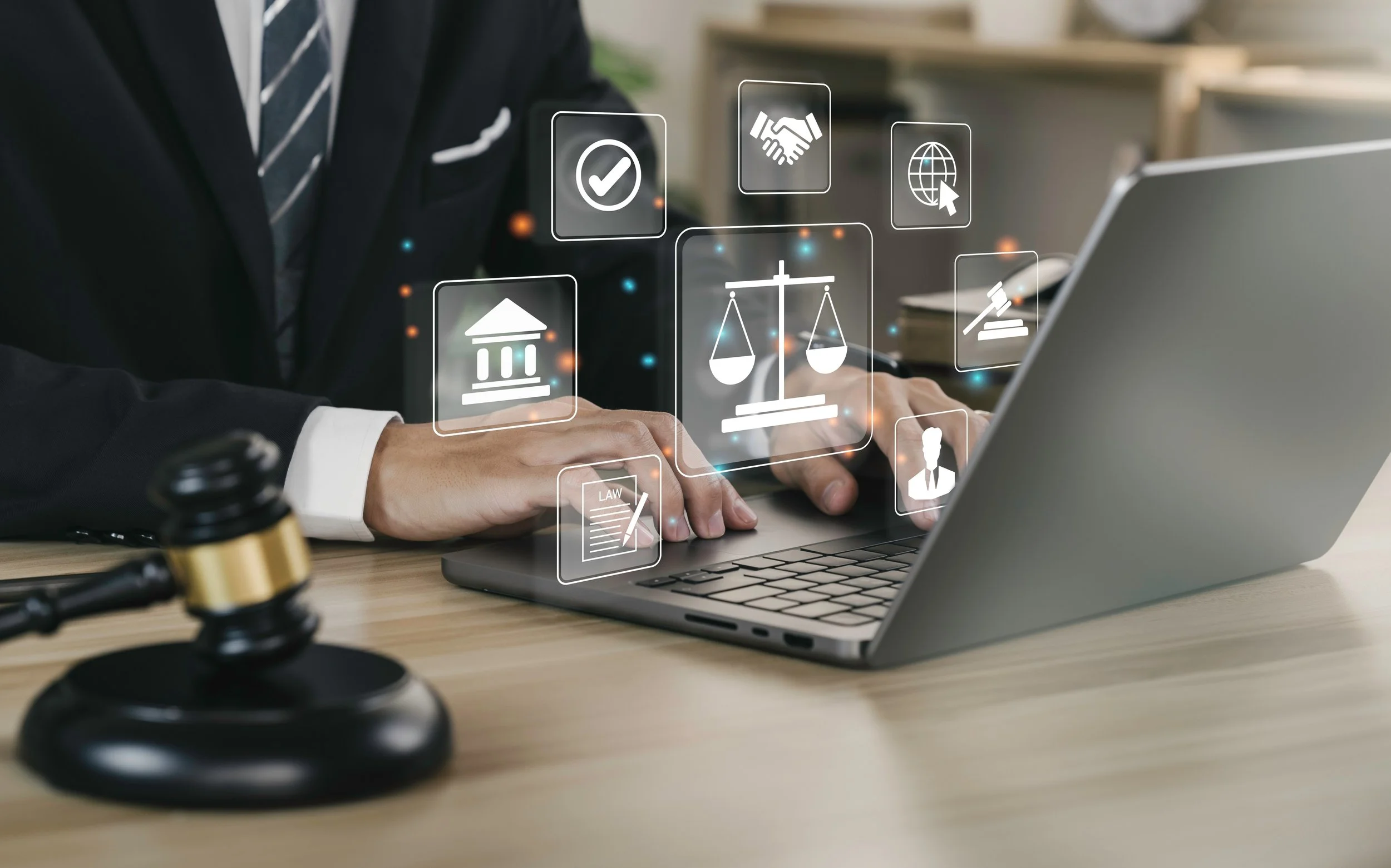 A person in a suit working on a laptop with digital legal and justice icons, including gavel, courthouse, scales, and law document, floating above the keyboard.