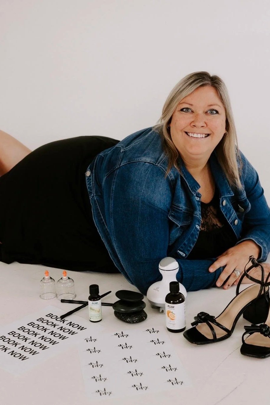 A woman with shoulder-length brown hair and blue eyes smiling, wearing a light blue lace-trimmed dress against a black background.