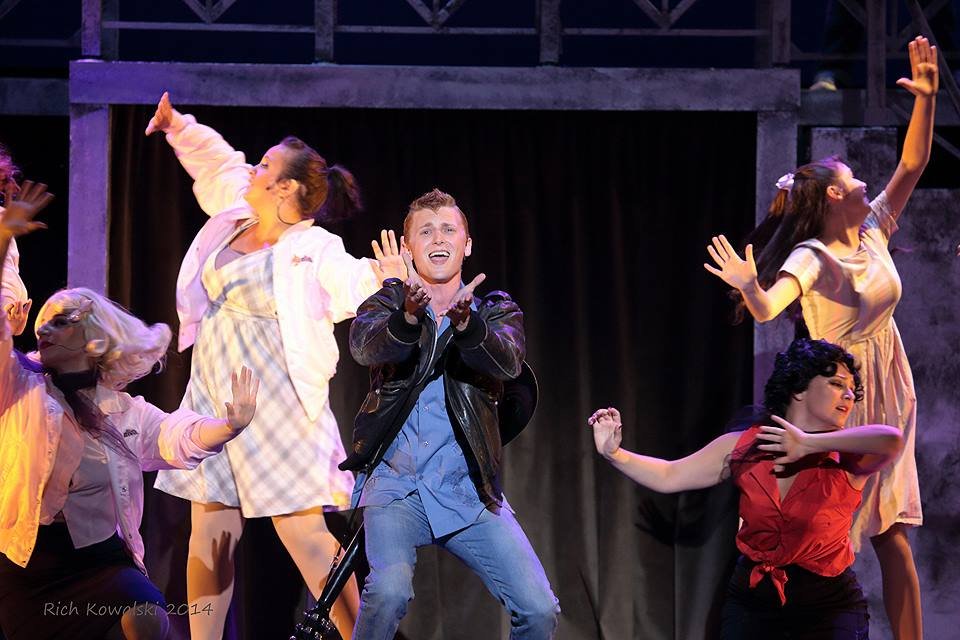 Group of young performers dancing on stage, some with their hands raised and expressive facial expressions. Grease Doody Count Basie Theatre