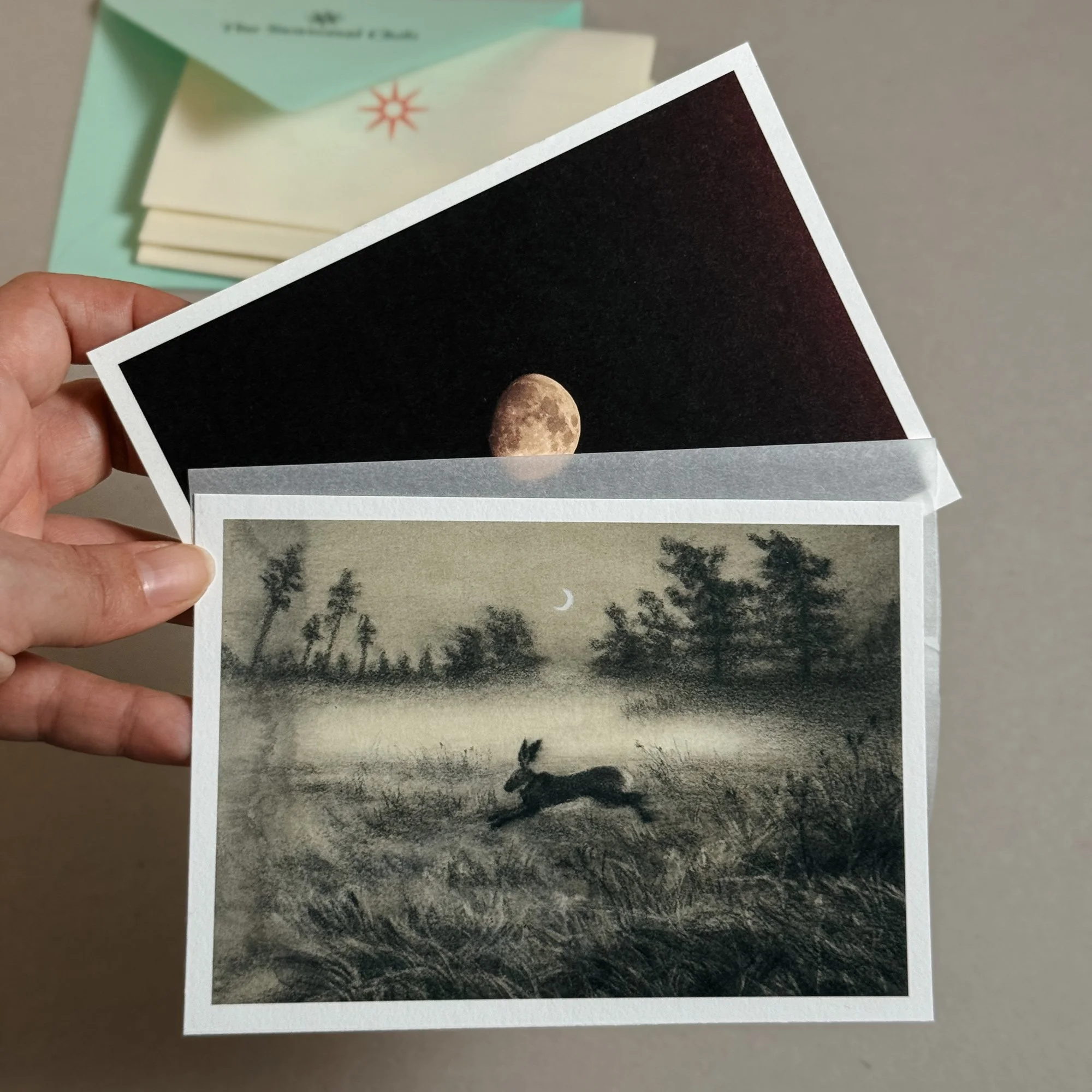 display of an art print of an hare running in the field under the moon, together with a moon postcard