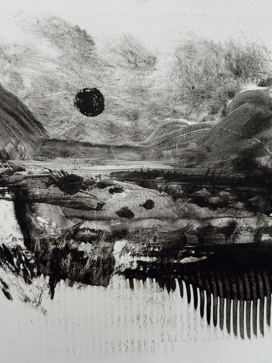 Black-and-white experimental monotype of a moody landscape: a black sun over textured hills, dark horizontal strokes across the middle, and comb-like vertical marks