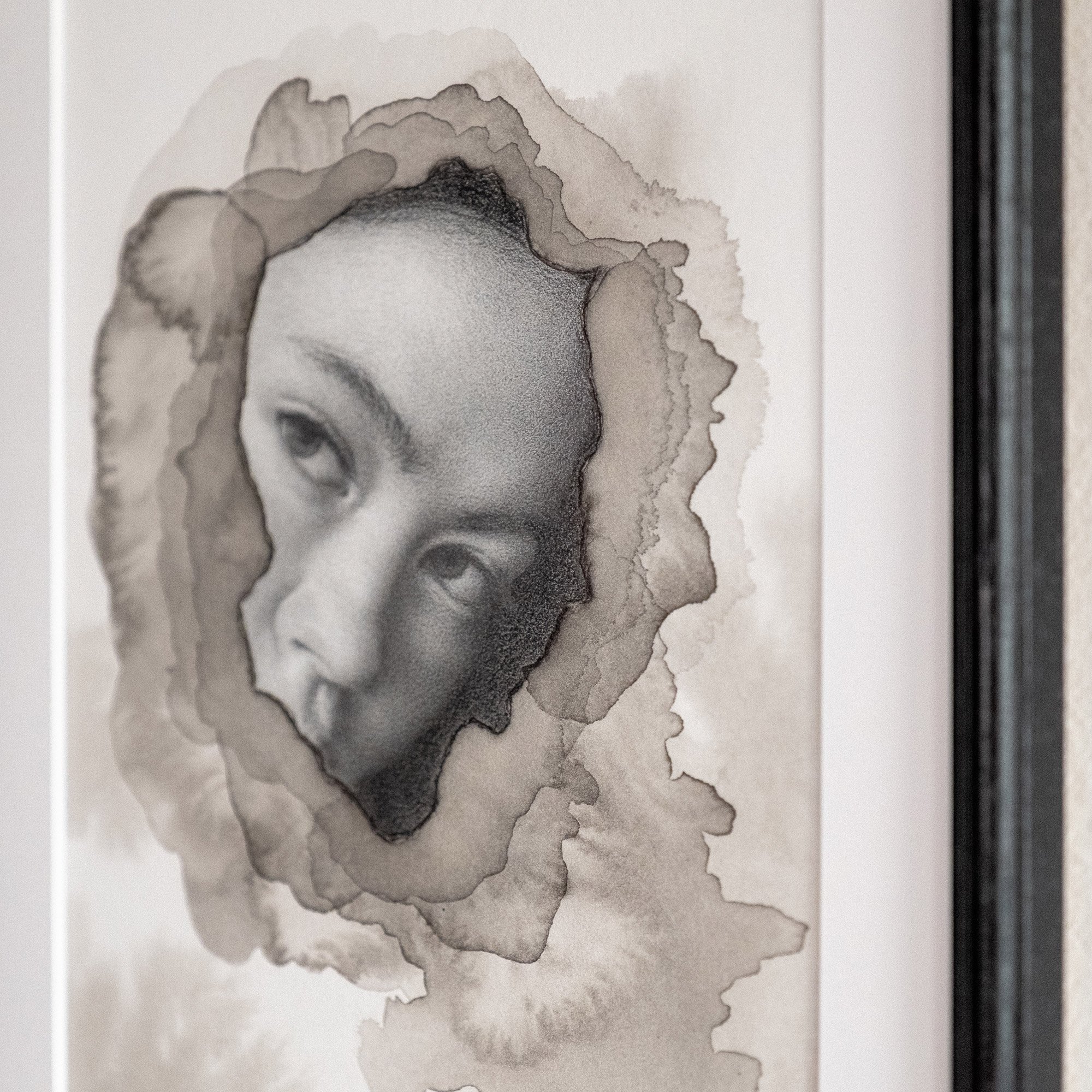 angle view of a framed original drawing, showing the portrait of a woman in graphite, surrounded by abstract ink textures