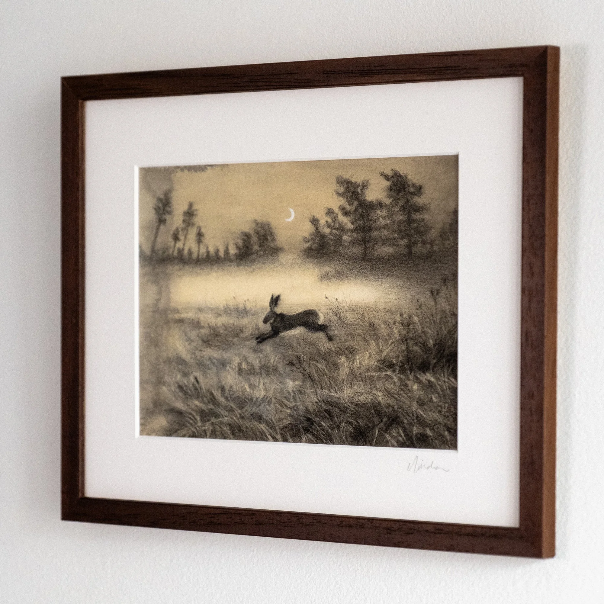 side view of a framed original charcoal drawing of a hare leaping across a field under the moonlight, representing a leap of faith