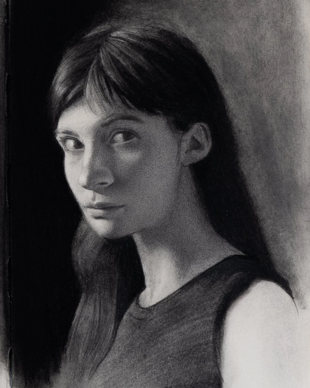 A black and white graphite portrait of a young woman with long hair, looking over her shoulder.