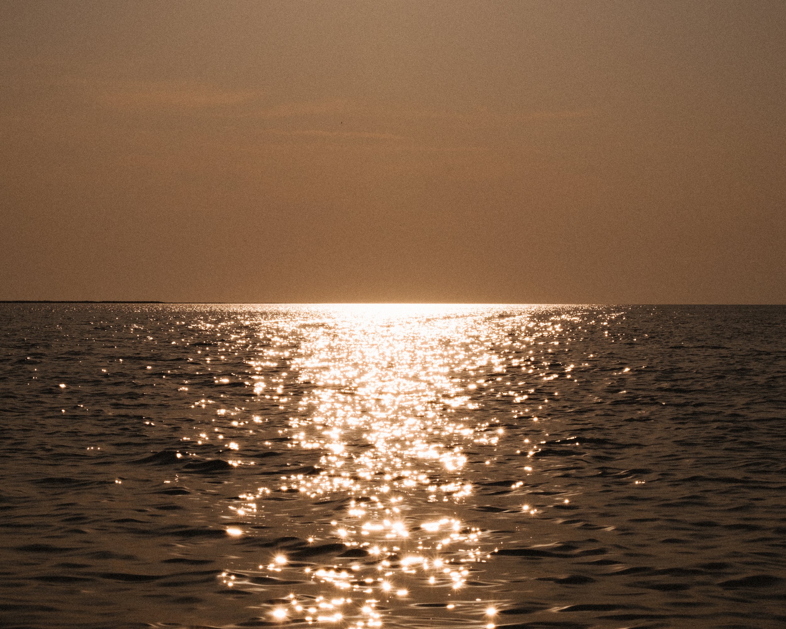 Sunrise over the sea, with sunlight reflecting on the water's surface.