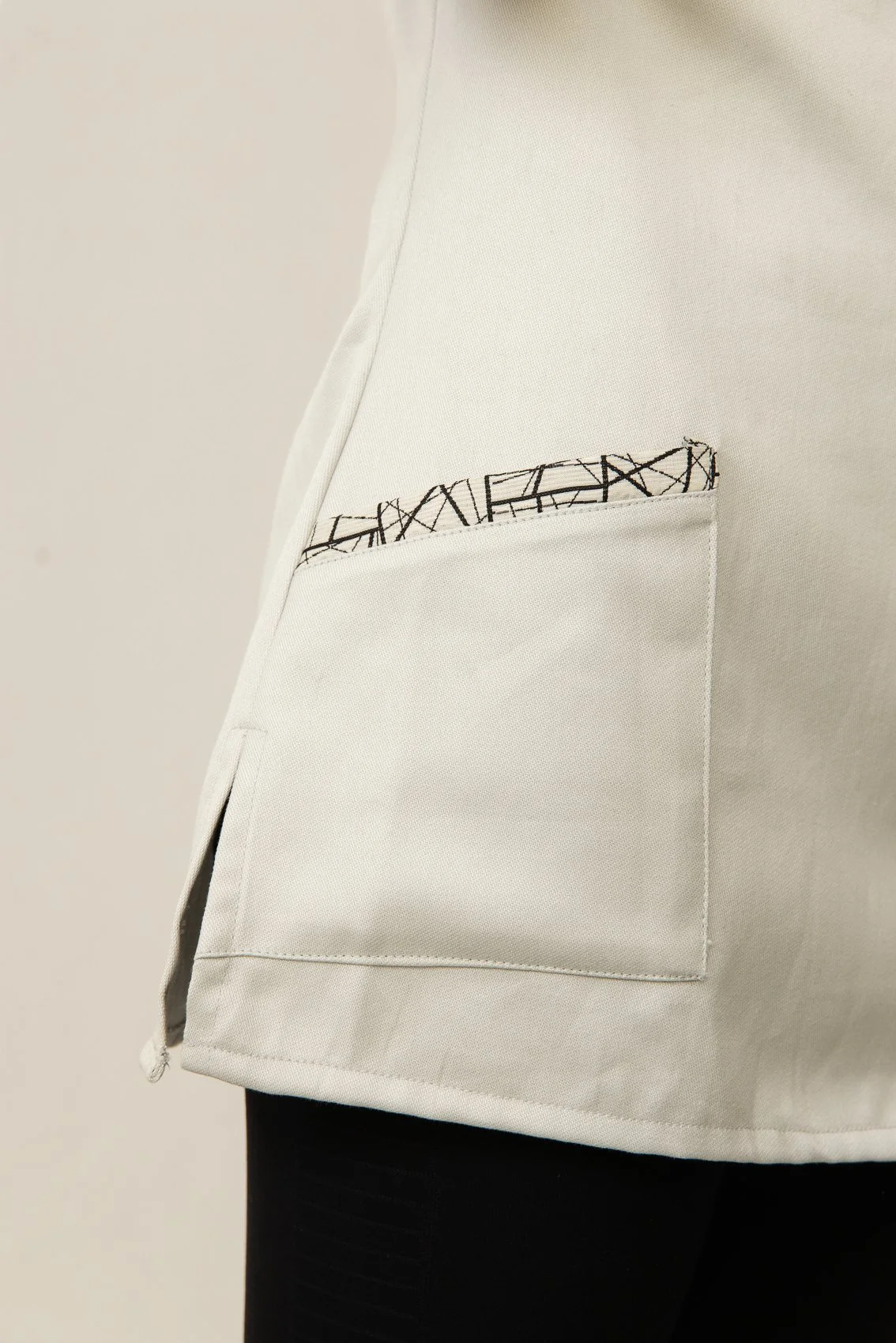 Blouse médicale blanche avec une poche à l'avant, contenant un tissu imprimé avec des lettres.