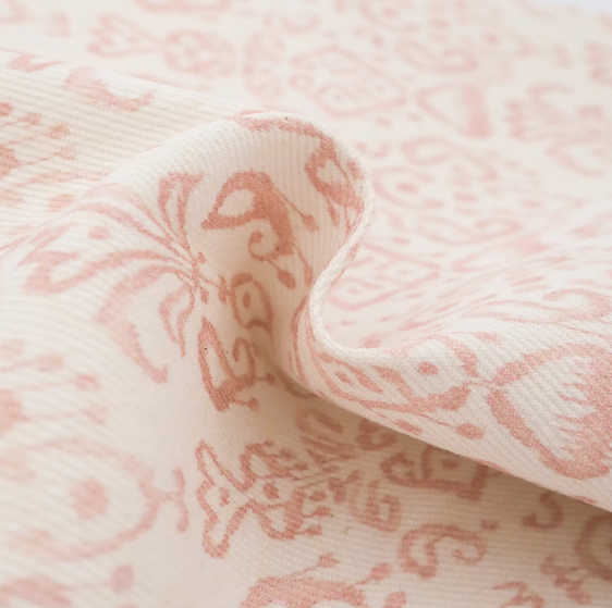 Tissu en coton avec un motif floral rose clair sur fond blanc.
