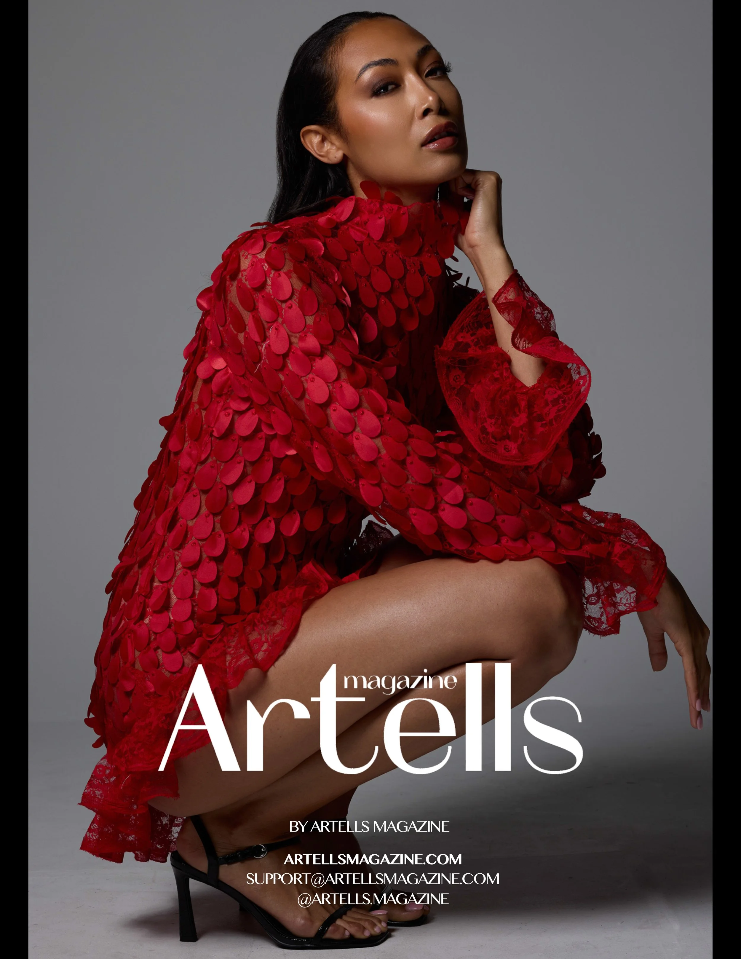 Cover of Artells Magazine featuring a woman in a red, textured dress with a high slit, squatting on a gray background.
