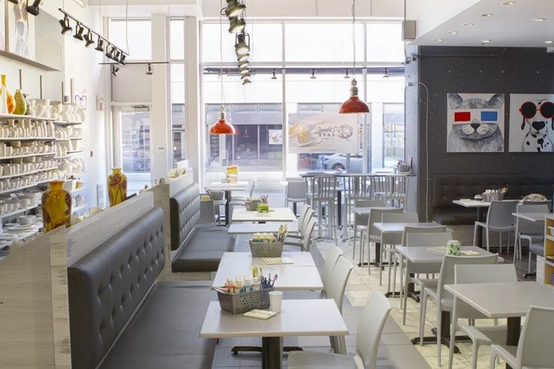 Salle à manger de café ou restaurant moderne avec tables, chaises, décor coloré et affiches d'art sur les murs.