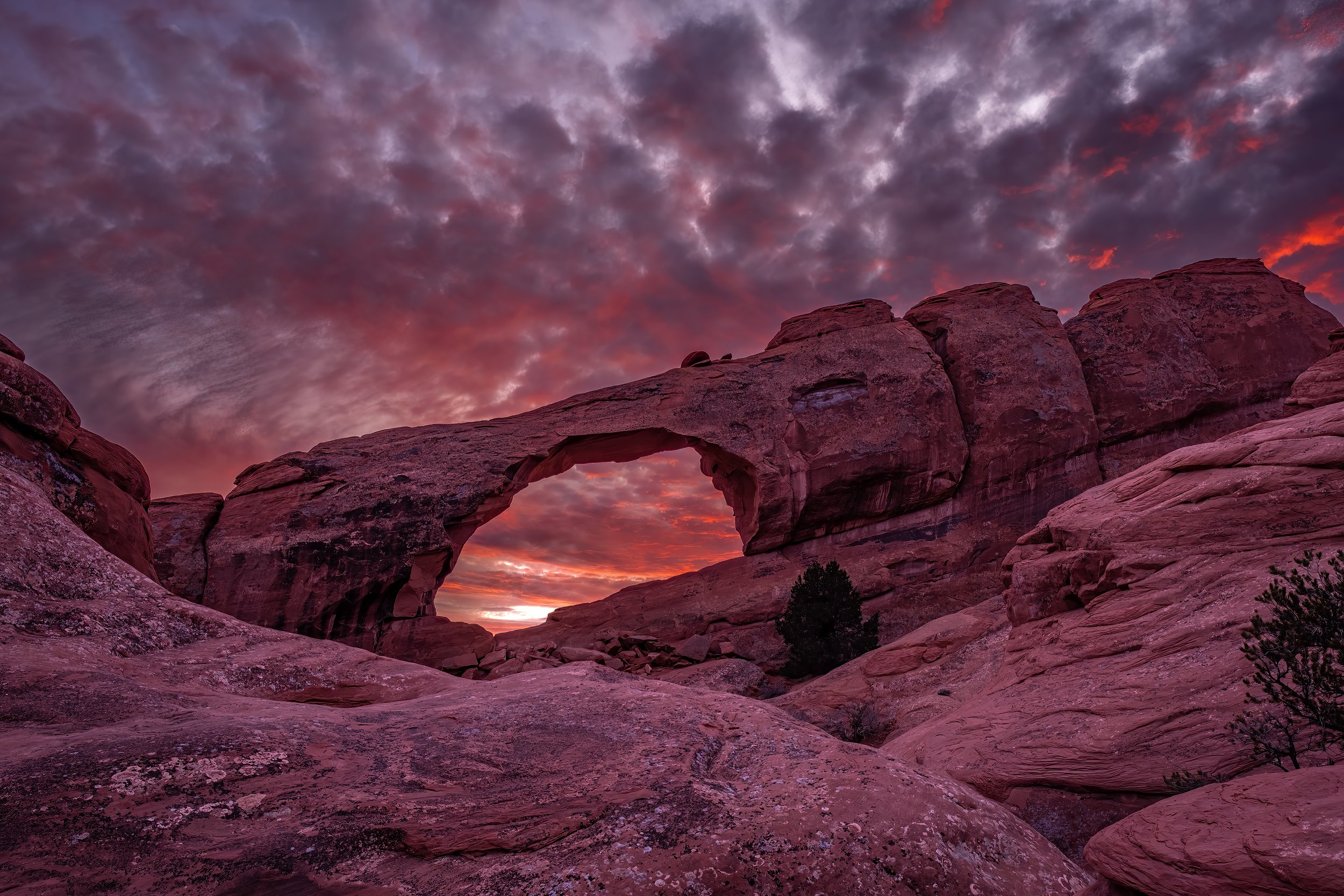 Perfect clouds behind a red rock arch.