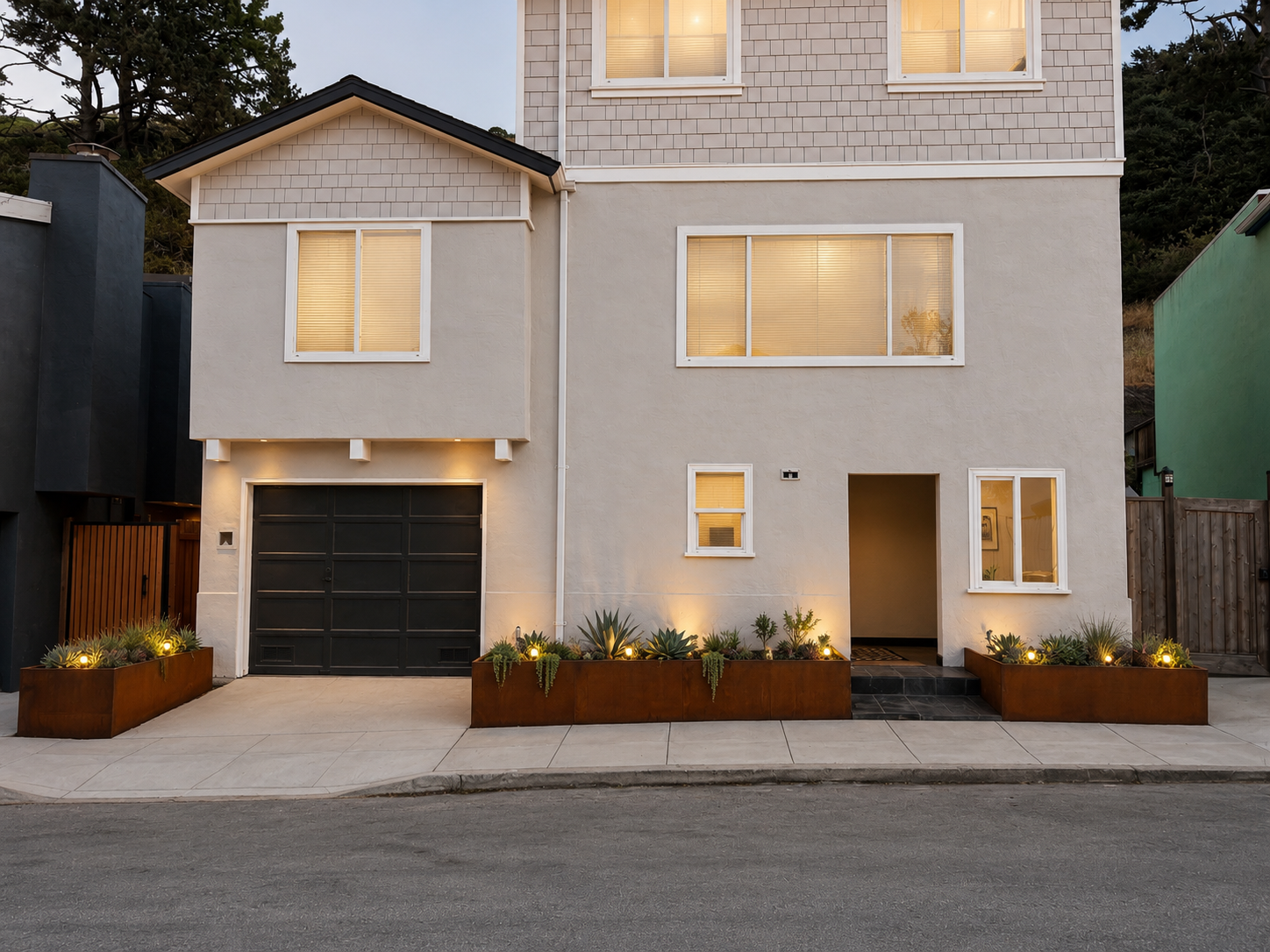 Modern multi-story house with a white exterior, black garage door, and landscaped front yard with plants and outdoor lighting.