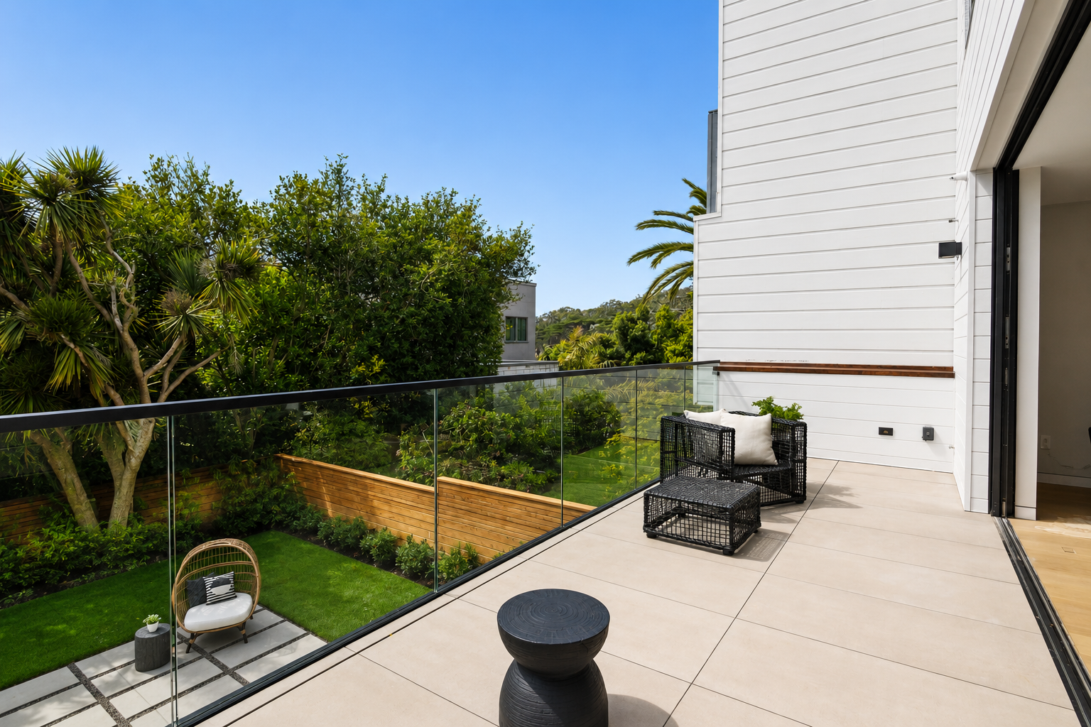 Modern balcony with outdoor seating and view of lush garden.