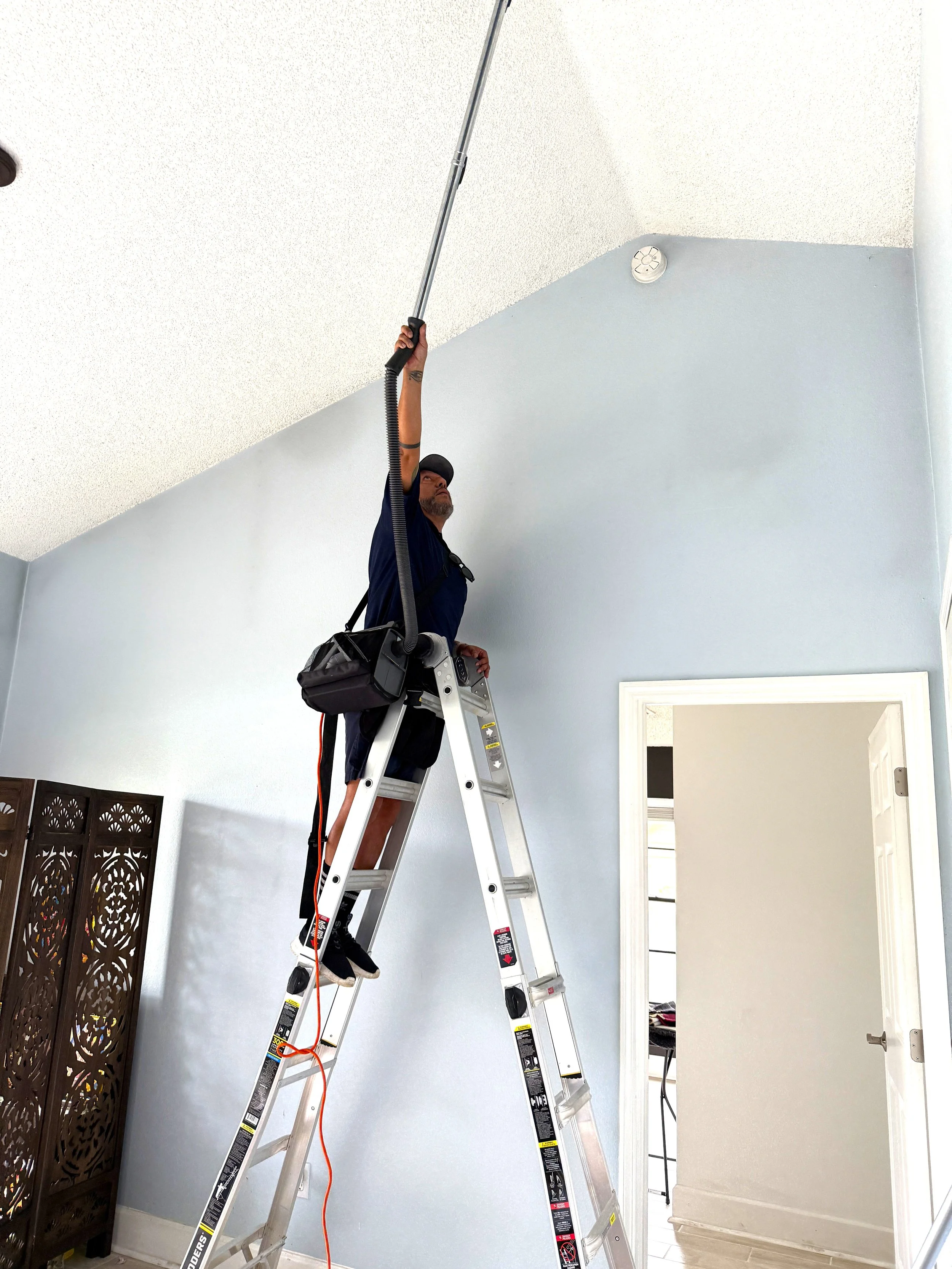 Modern white kitchen with marble backsplash, stainless steel refrigerator, gas stove, coffee machine, and minimalist decor.