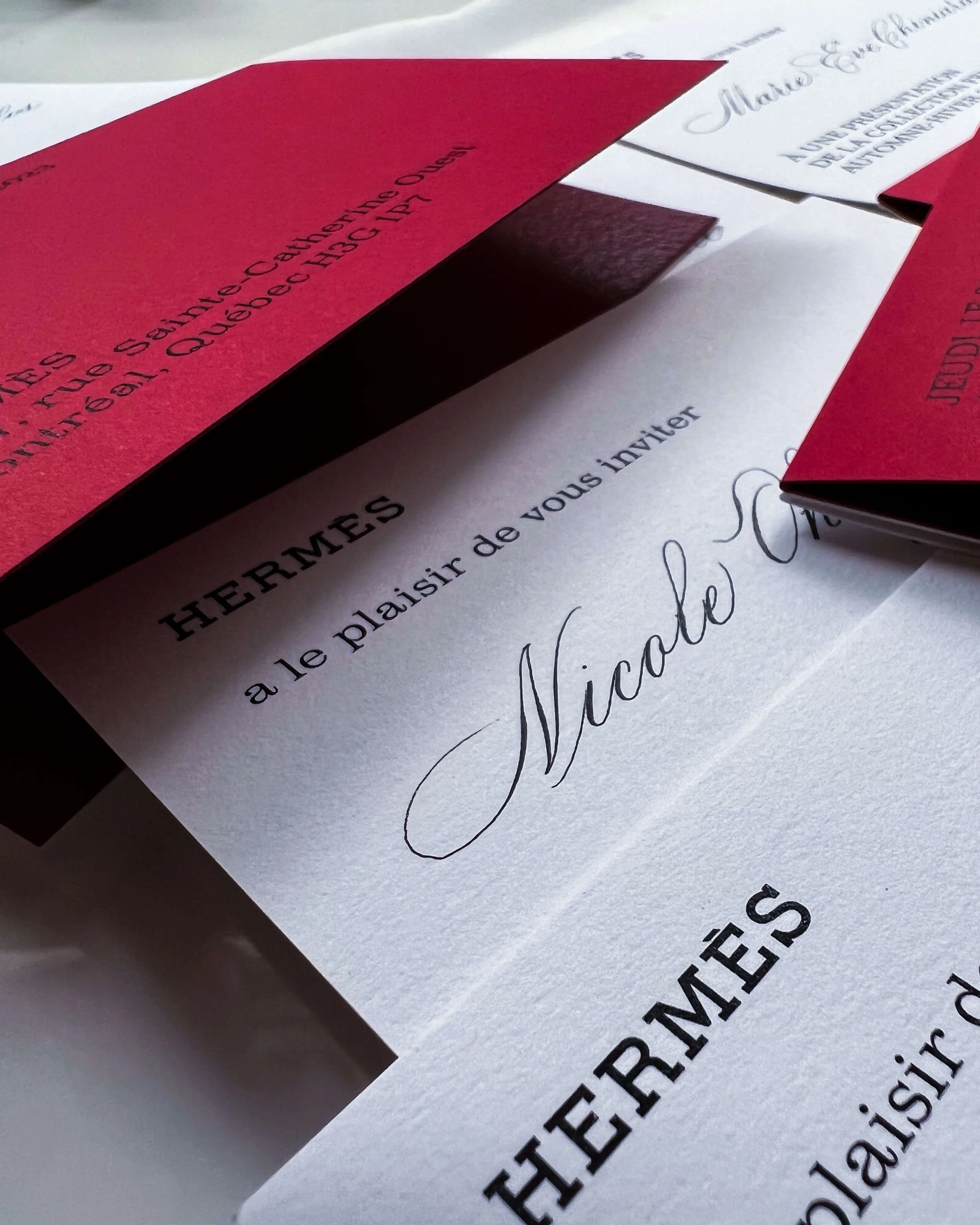 Invitation cards from Hermès written in classic script, placed on a table.