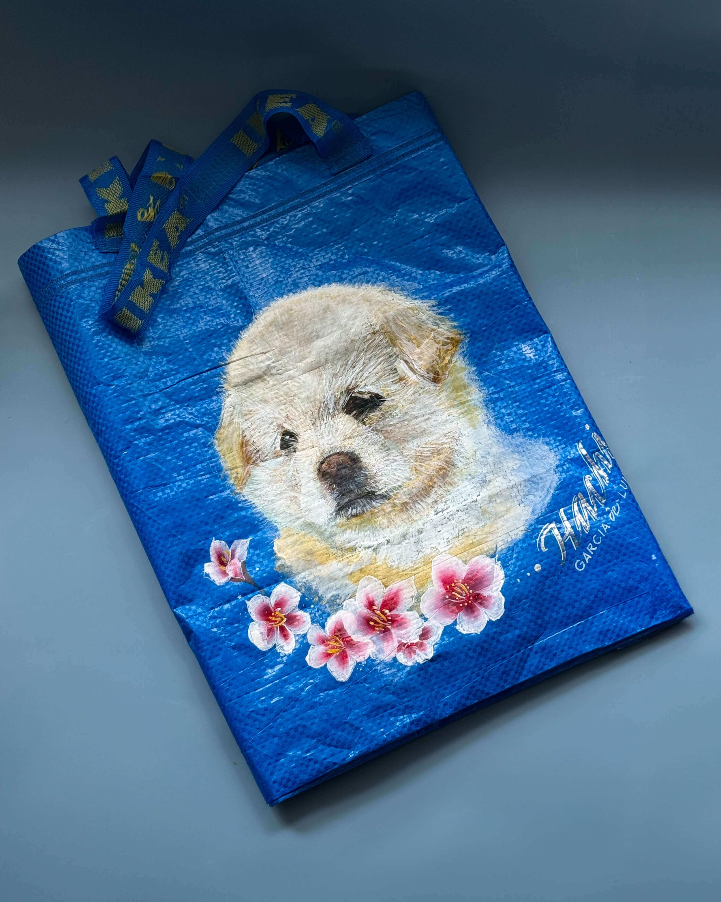 Blue IKEA reusable shopping bag with a puppy's face and pink flowers printed on it.