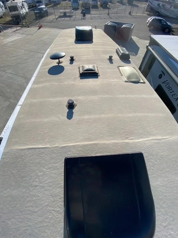 Top view of a RV roof with various vents, skylights, and antennas.
