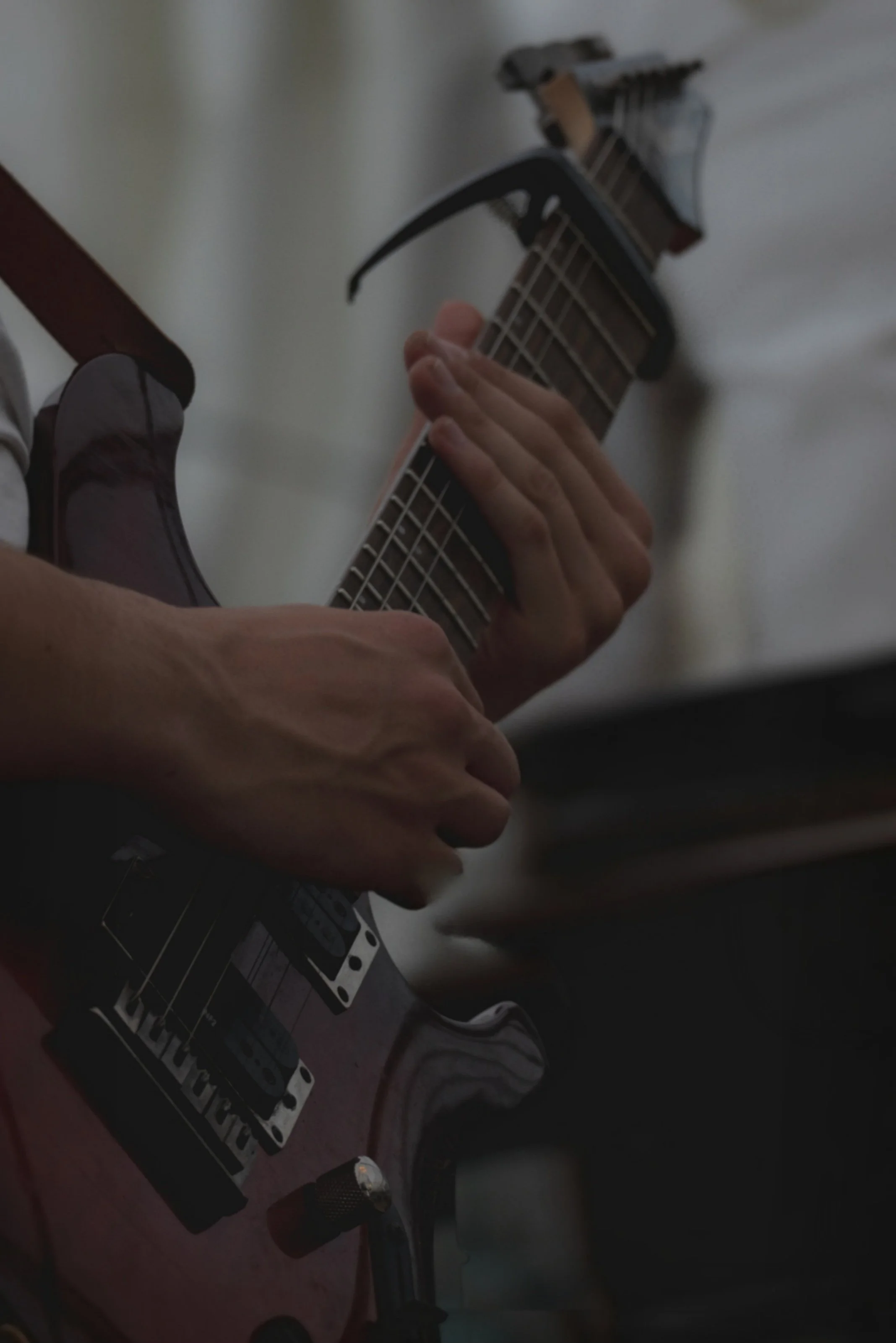 Nahaufnahme von einer Person, die auf einer E-Gitarre spielt, nur die Hände und ein Teil des Gitarrenkörpers sind sichtbar.