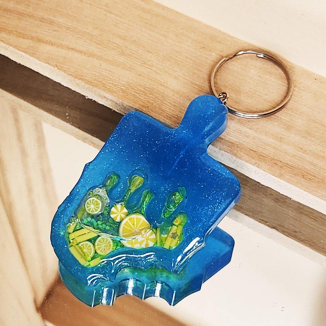 Lemon popsicle wet shaker keychain
Blue resin popsicle with clear resin sealer top, filled with foam citrus slices, foam sprinkles, and glitter (inner liquid is baby oil)