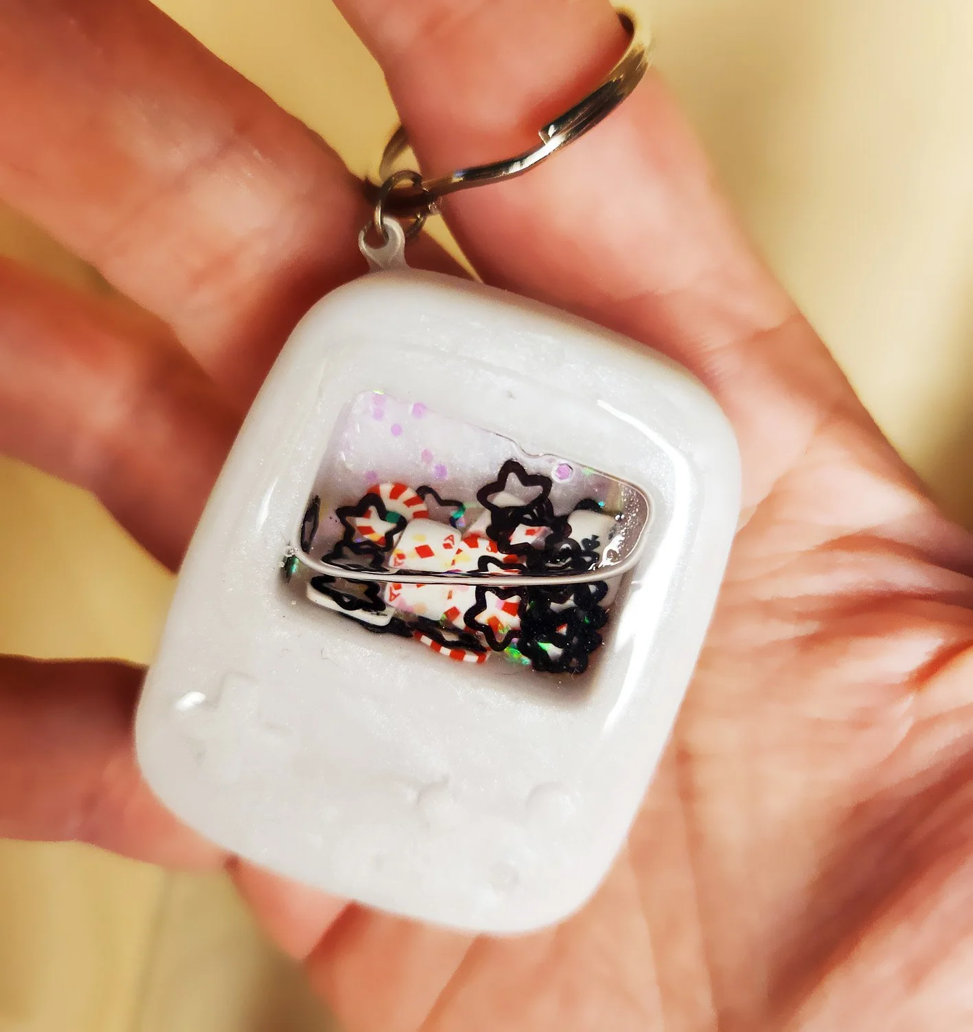 Poker player wet shaker keychain
White resin handheld game with clear resin sealer top, filled with glitter, foam playing cards, foam poker chips, and stars (inner liquid is baby oil)