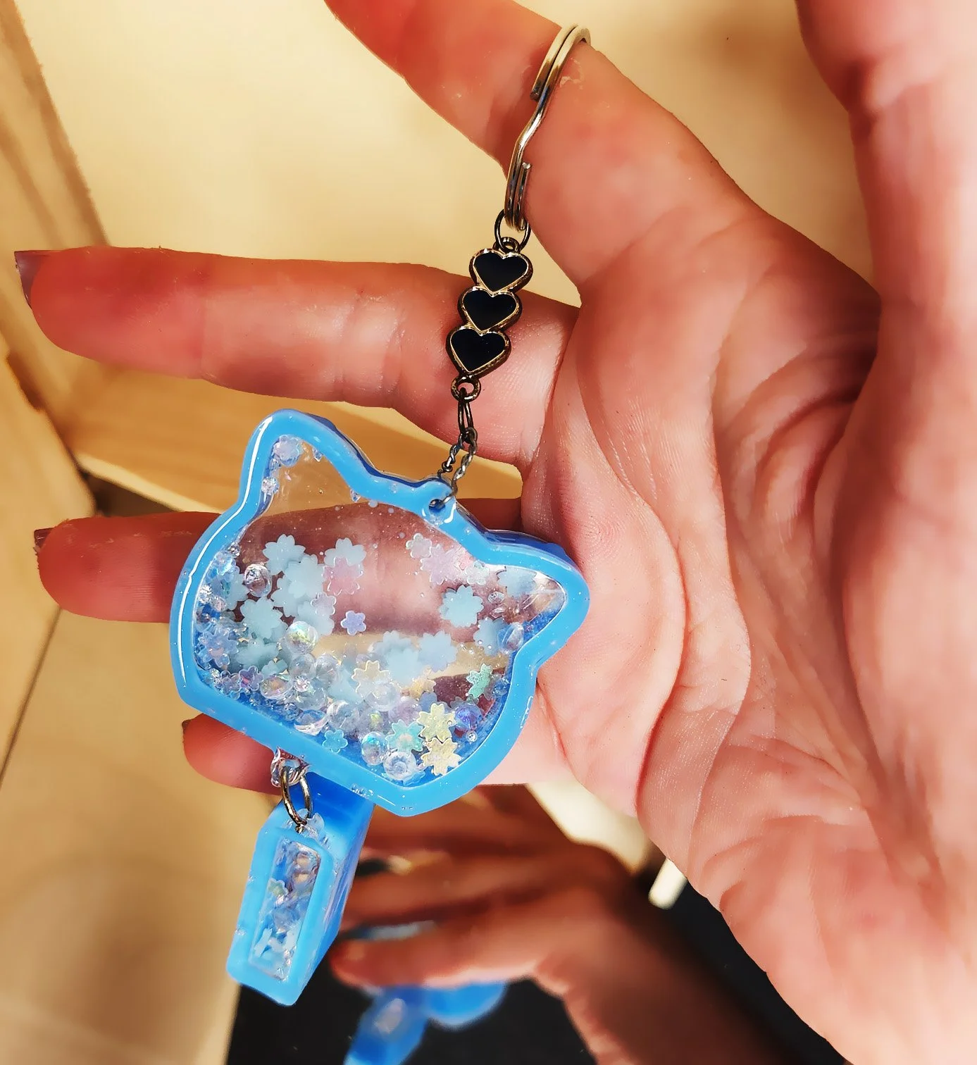Celebration cat dry shaker keychain
Clear resin with blue edges in the shape of a cat head plus a tassel, filled with glitter, rhinestones, and glow-in-the-dark foam snowflakes
