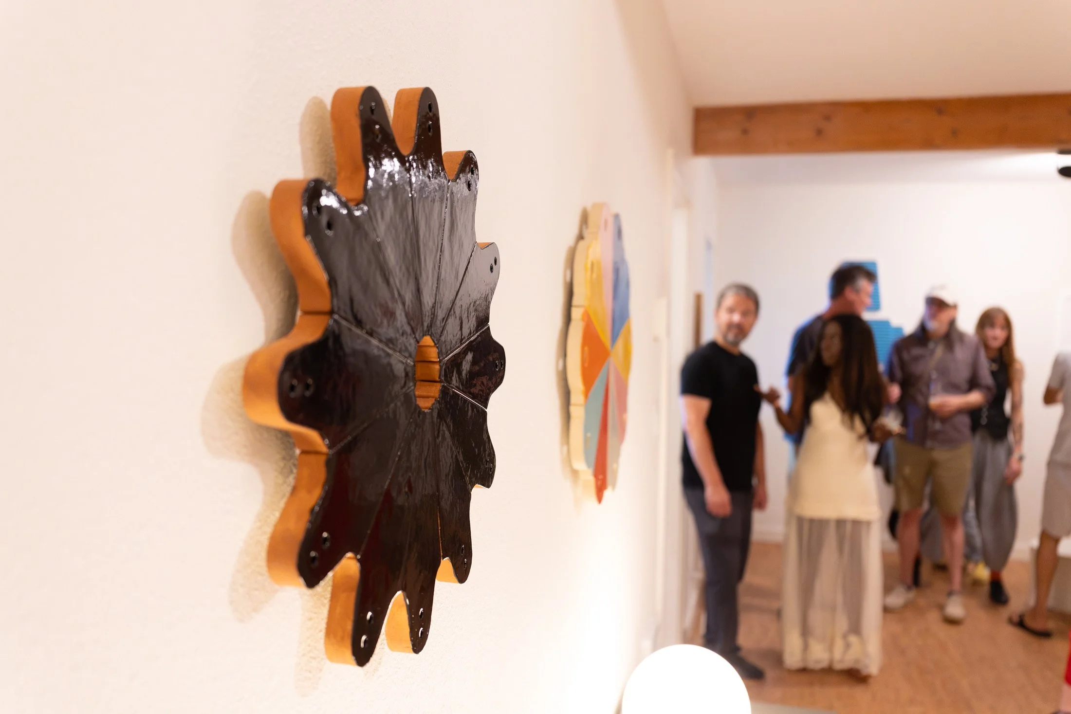 Artwork by Michael Rey on exhibit with people in the background at the opening of RecRoom, an art gallery in Eugene.