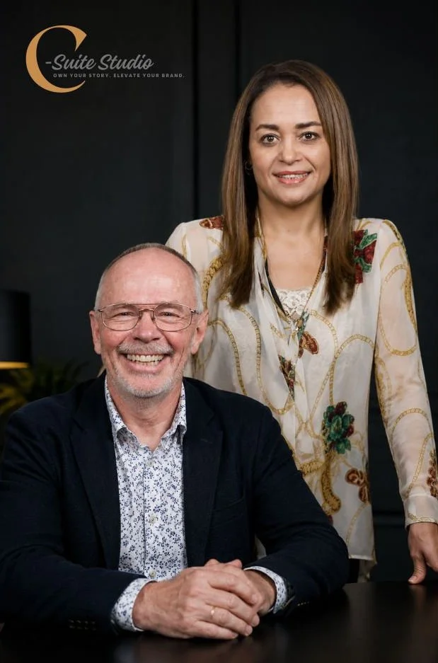 A woman and a man posing together in a professional setting, with a logo that reads 'C-Suite Studio' in the top left corner.